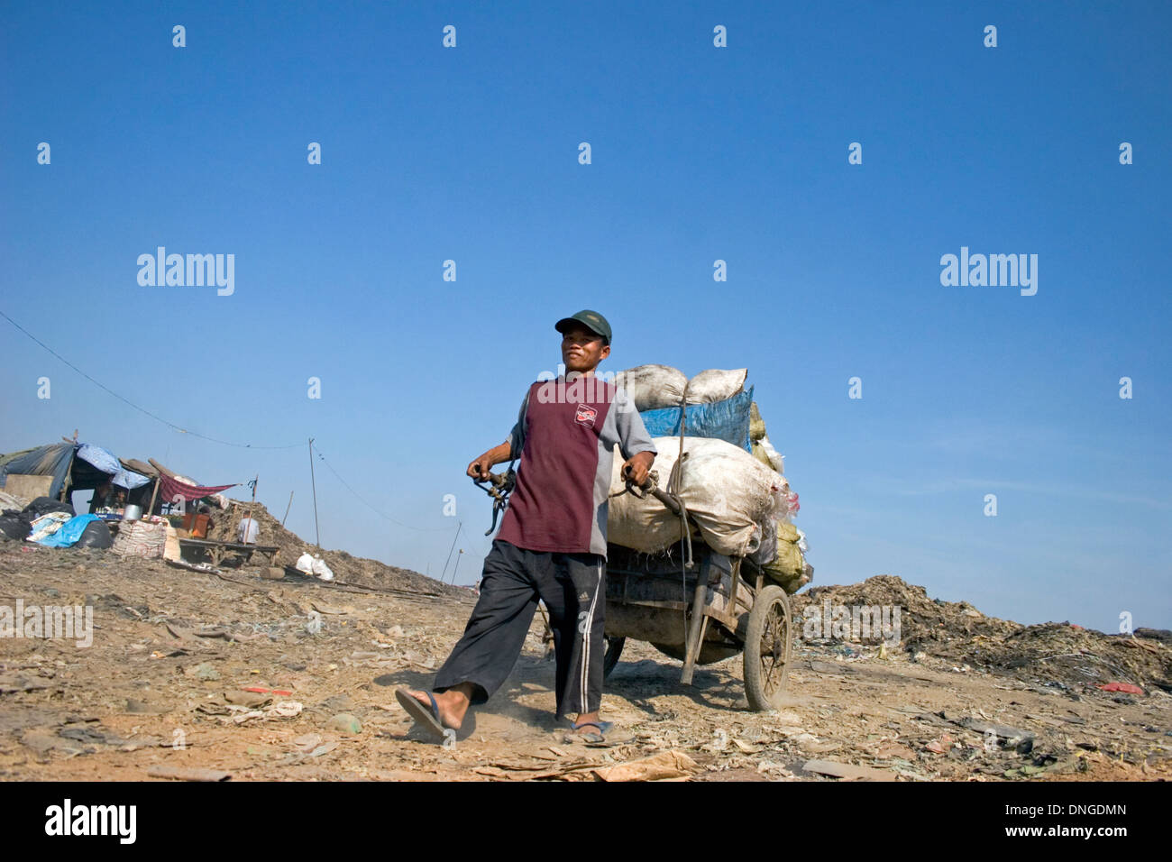 Un homme tire un gros panier rempli de sacs à la décharge de Stung Meanchey toxiques à Phnom Penh, Cambodge. Banque D'Images