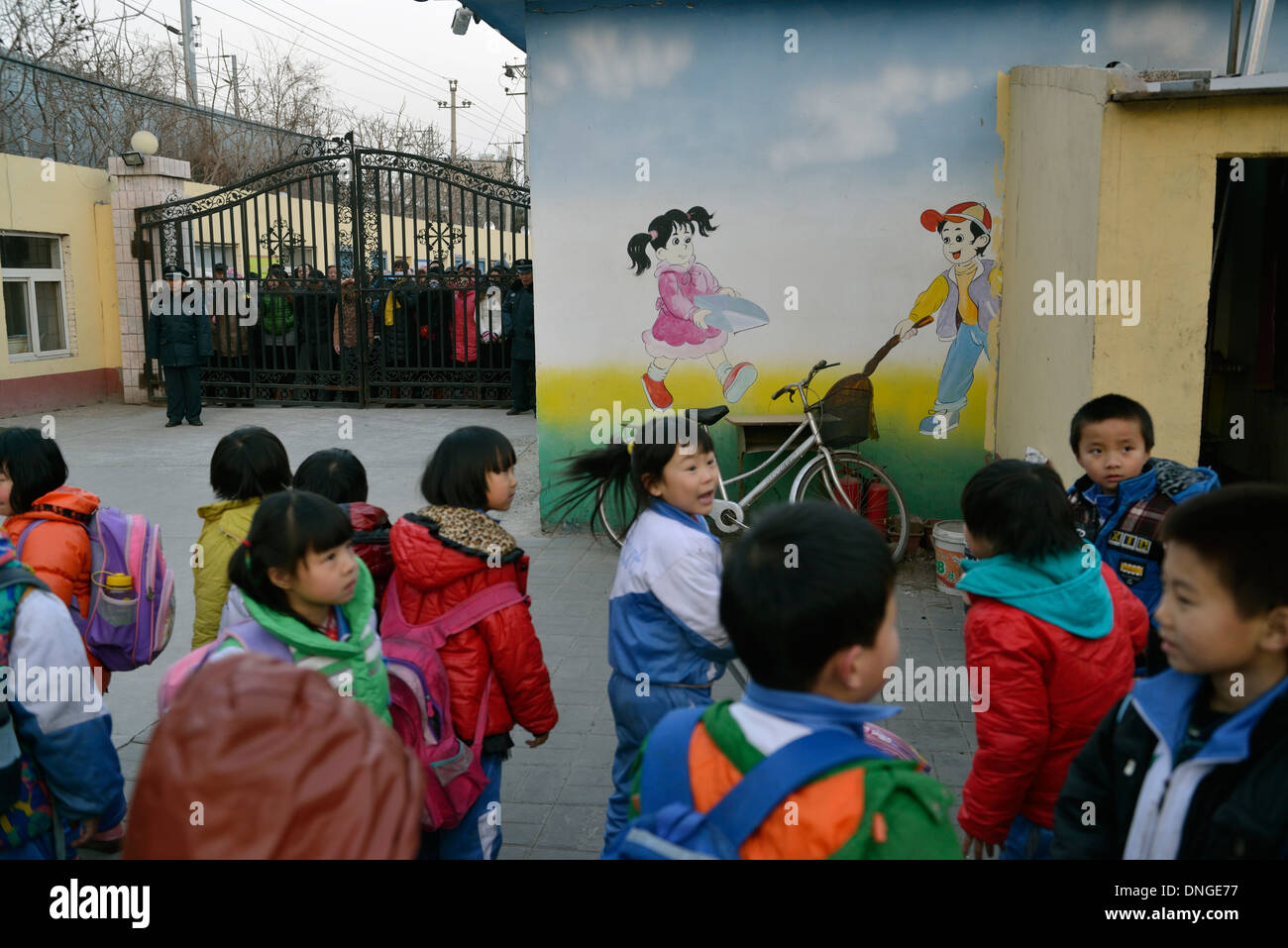 Les parents attendent pour aller chercher leurs enfants à l'extérieur de la porte d'une école de migrants lorsqu'il n'y a plus de cours à Beijing. 25-Déc-2013 Banque D'Images