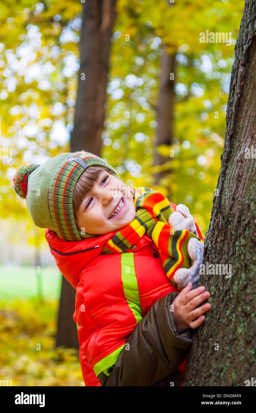 Heureux l'enfant souriant et se cachant dans autumn park Banque D'Images