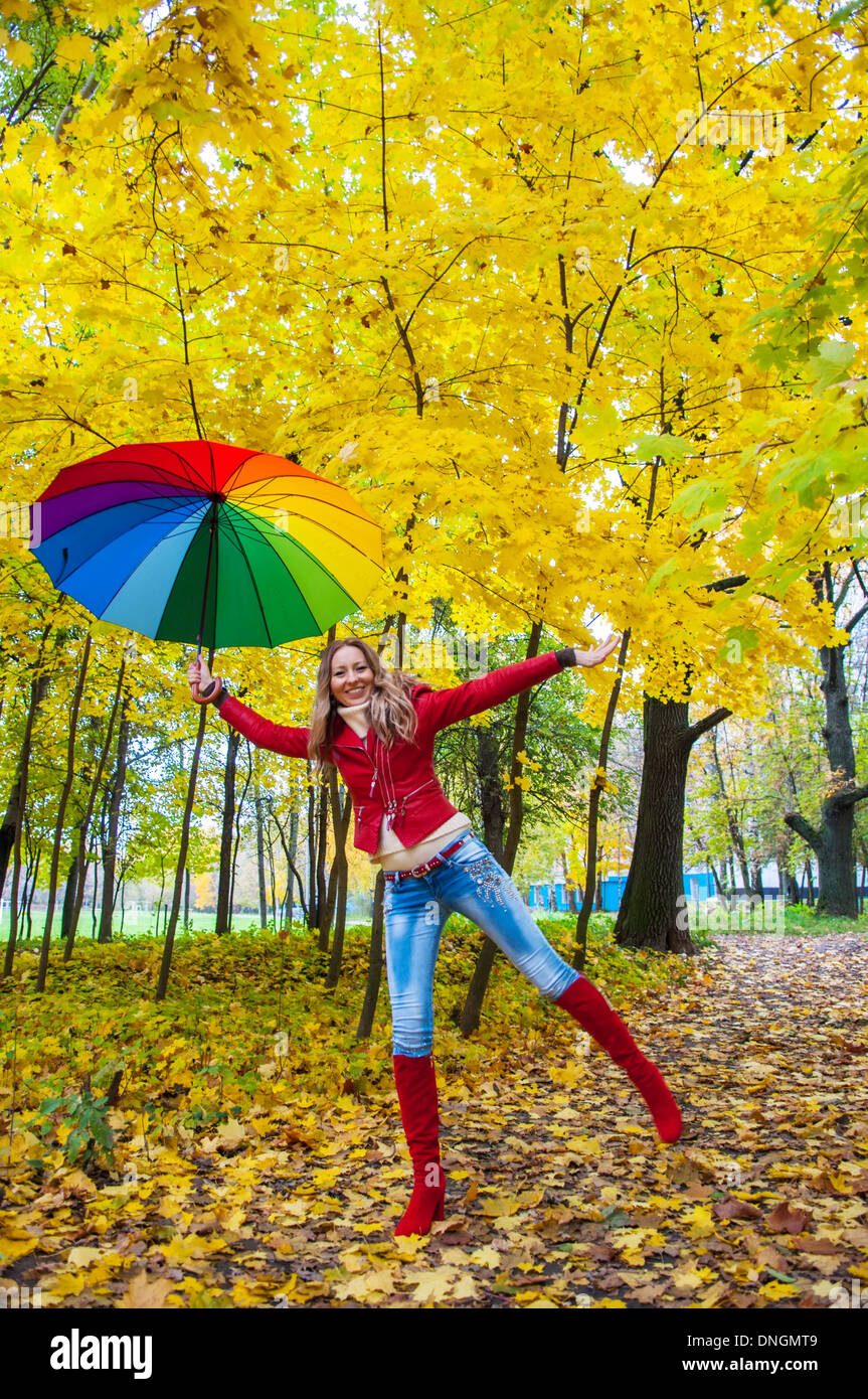 Jolie fille avec un parapluie multicolore en automne park Banque D'Images