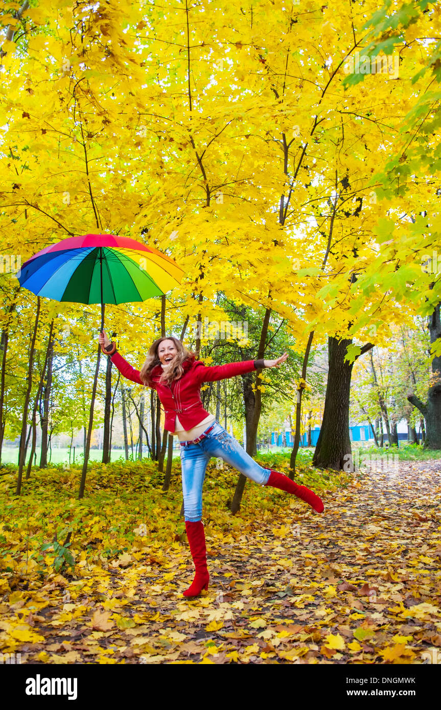 Jolie fille avec un parapluie multicolore en automne park Banque D'Images