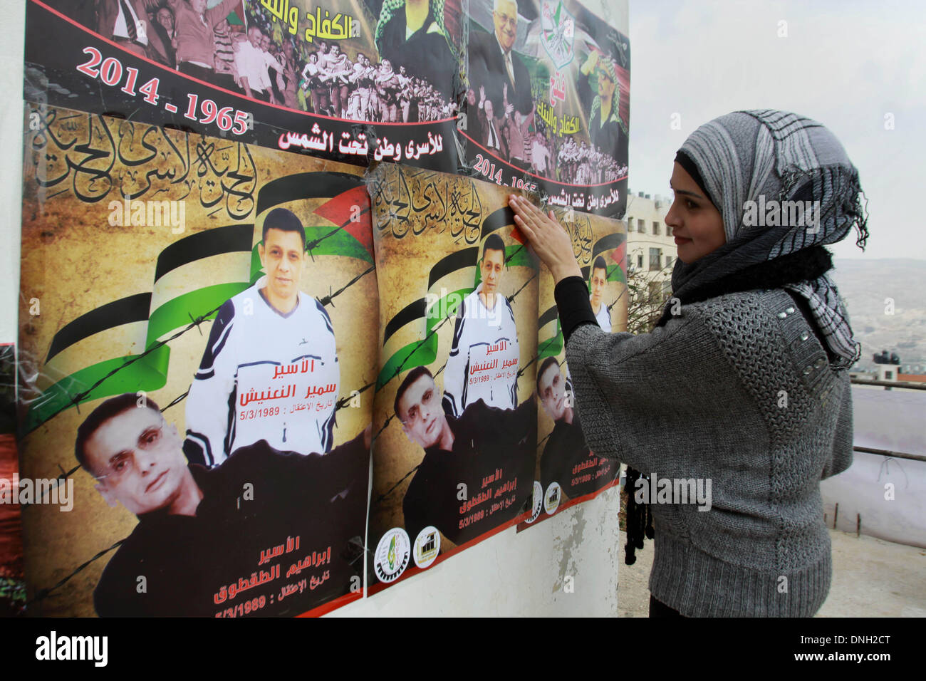 Naplouse, Cisjordanie, . Dec 29, 2013. Une femme palestinienne est suspendu une bannière représentant prisonnier palestinien Ibrahim Tqtoq l'extérieur de sa maison, dans la ville cisjordanienne de Naplouse, le dimanche. Le service pénitentiaire israélien publié samedi soir sur son site internet une liste de 26 prisonniers palestiniens vétéran prévue pour lundi comme un troisième groupe de prisonniers qui ont été arrêtés avant les Accords d'Oslo de 1994. Credit : Nedal Eshtayah ZUMAPRESS.com/Alamy Images/APA/Live News Banque D'Images Naplouse, Cisjordanie, . Dec 29, 2013. Une femme palestinienne est suspendu une bannière représentant prisonnier palestinien Ibrahim Tqtoq l'extérieur de sa maison, dans la ville cisjordanienne de Naplouse, le dimanche. Le service pénitentiaire israélien publié samedi soir sur son site internet une liste de 26 prisonniers palestiniens vétéran prévue pour lundi comme un troisième groupe de prisonniers qui ont été arrêtés avant les Accords d'Oslo de 1994. Credit : Nedal Eshtayah ZUMAPRESS.com/Alamy Images/APA/Live News Banque D'Images