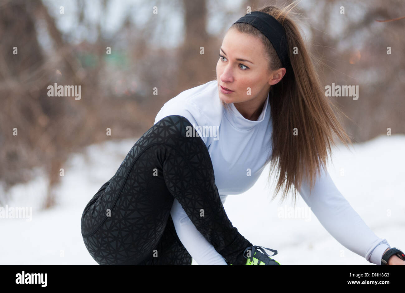 Une belle jeune femme s'étend avant une course sur un couvert de neige journée d'hiver. Banque D'Images