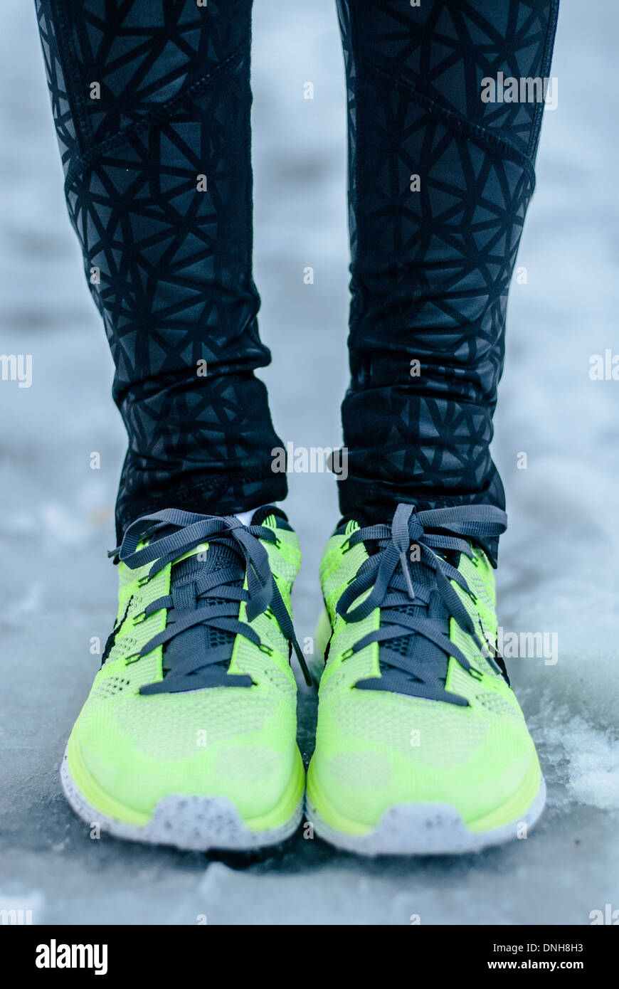 Libre de mettre en place les pieds du coureur, en néon jaune chaussures de course, comme elle se tient sur un chemin de glace sur une froide journée d'hiver. Banque D'Images