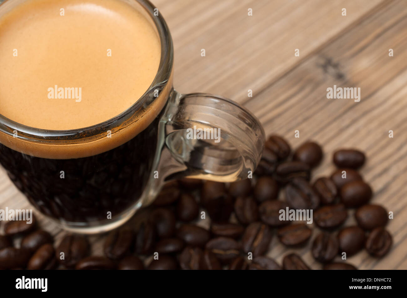 Tasse de café expresso en verre sur la table en bois avec café en grains - faible profondeur de champ Banque D'Images