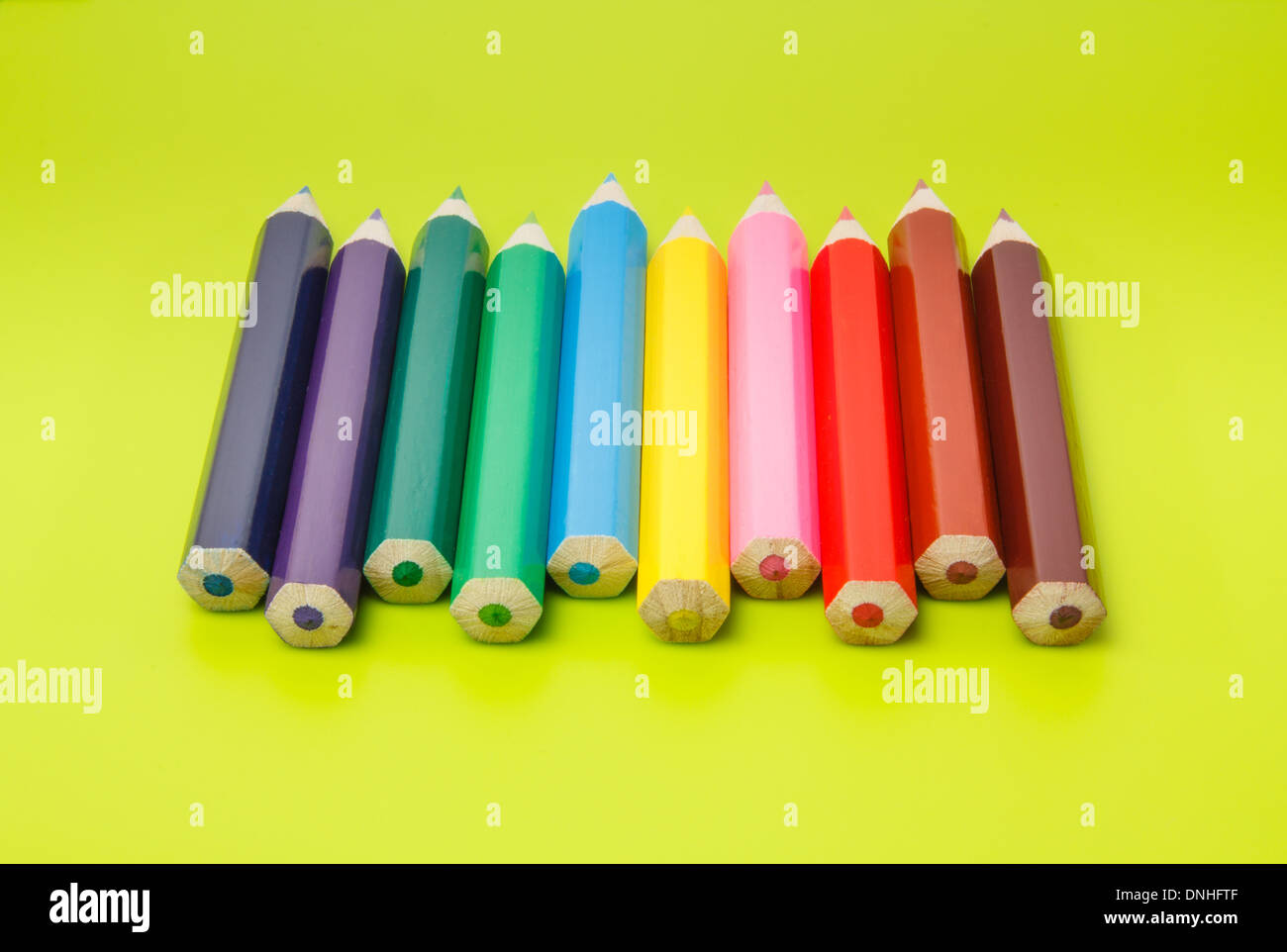 Les petits crayons côte à côte classés par couleurs sur fond vert olive Banque D'Images