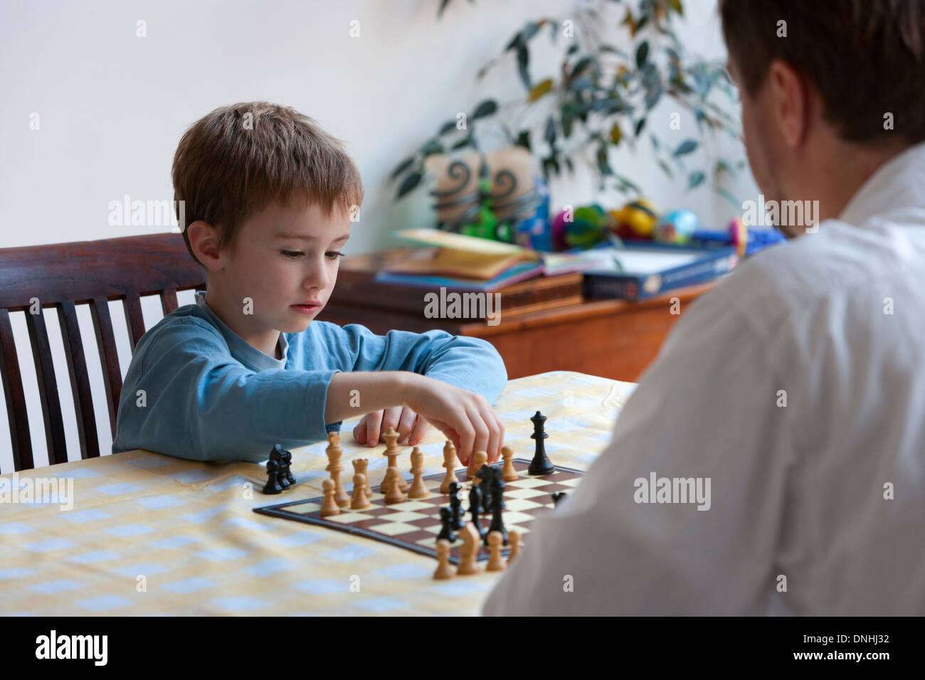 Père est jouer aux échecs avec son fils dans la cuisine Banque D'Images