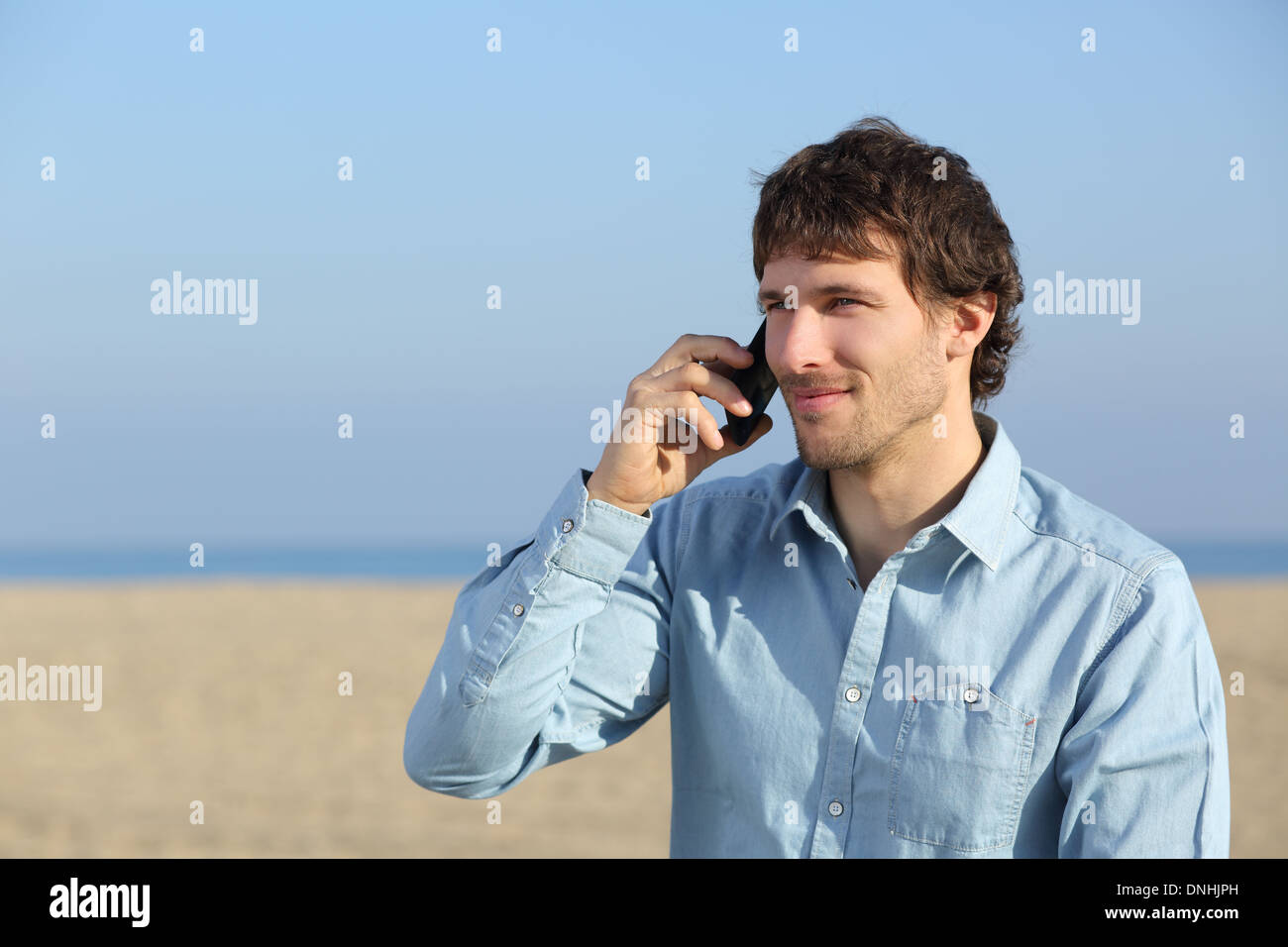 Homme séduisant au téléphone sur la plage isolé sur fond blanc Banque D'Images