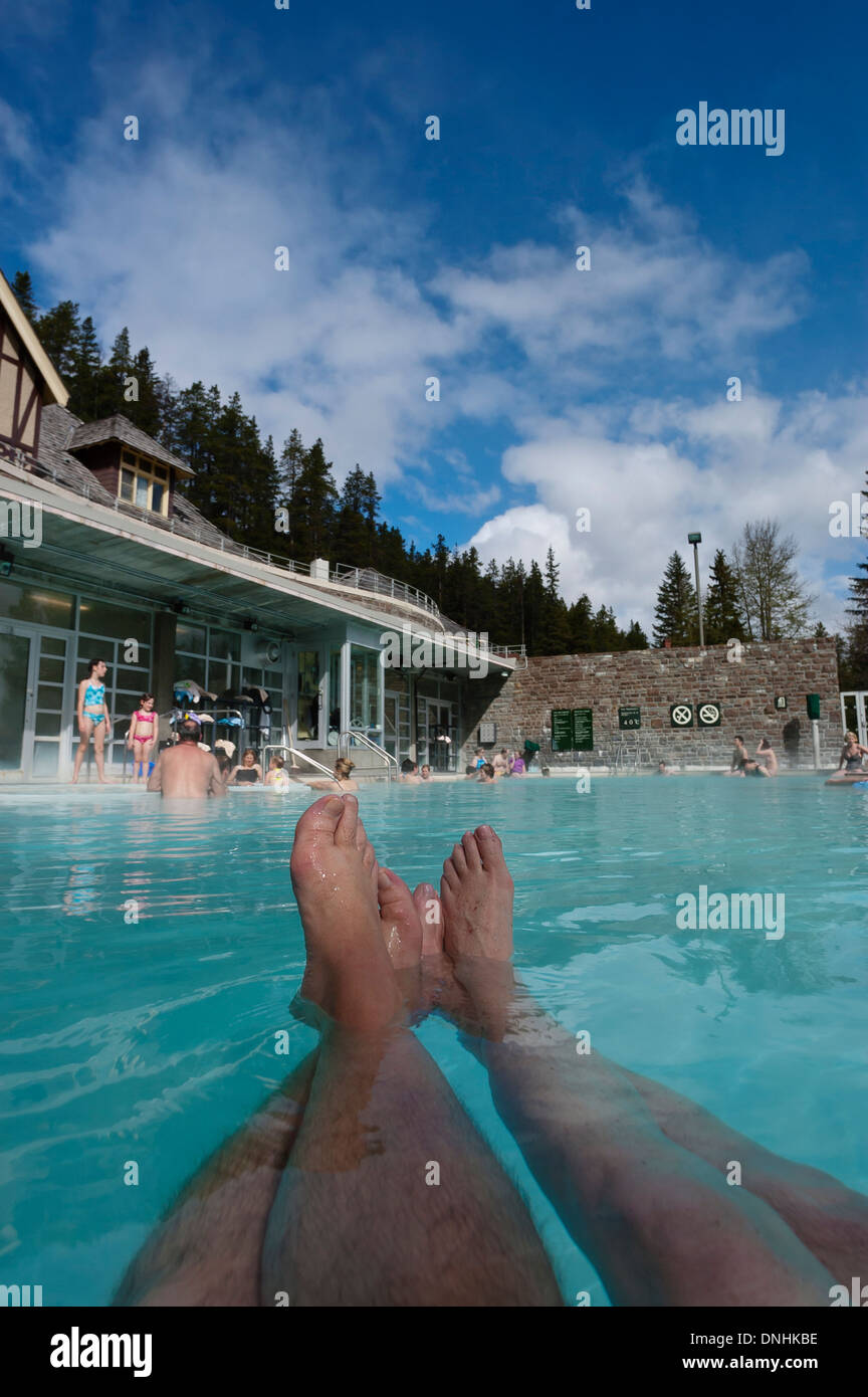 Deux adultes avec leurs les jambes allongées flottant dans Banff Upper Hot Springs. L'Alberta, Canada Banque D'Images