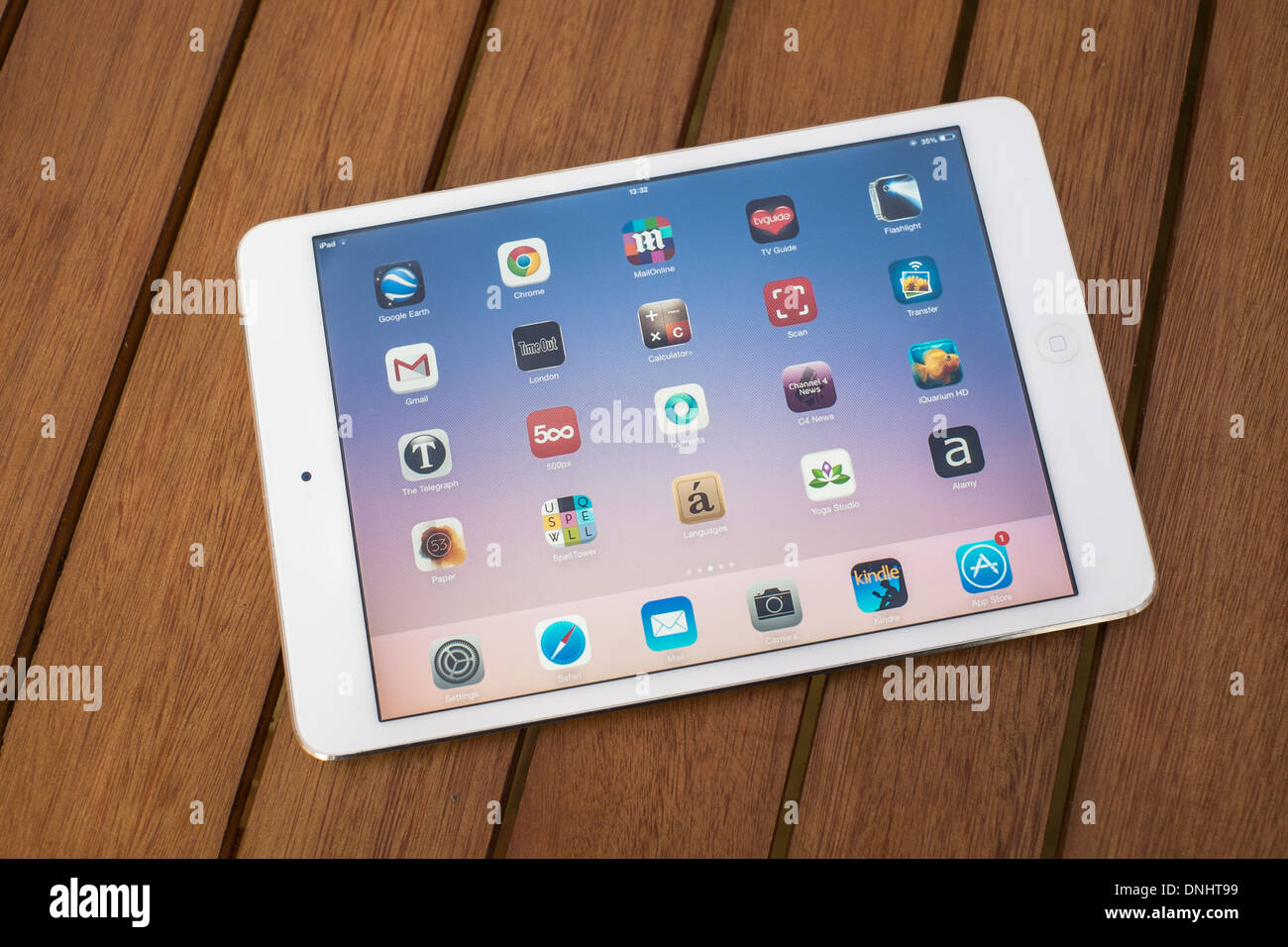 Ipad Mini blanc sur une table en bois montrant l'écran Applications. Banque D'Images