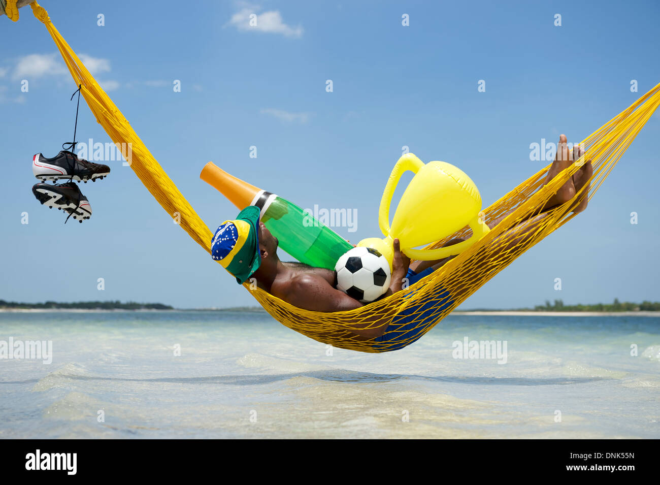 Le joueur de soccer brésilien Champion célébrer en vous relaxant dans son hamac avec football, bouteille de champagne, et le trophée Banque D'Images