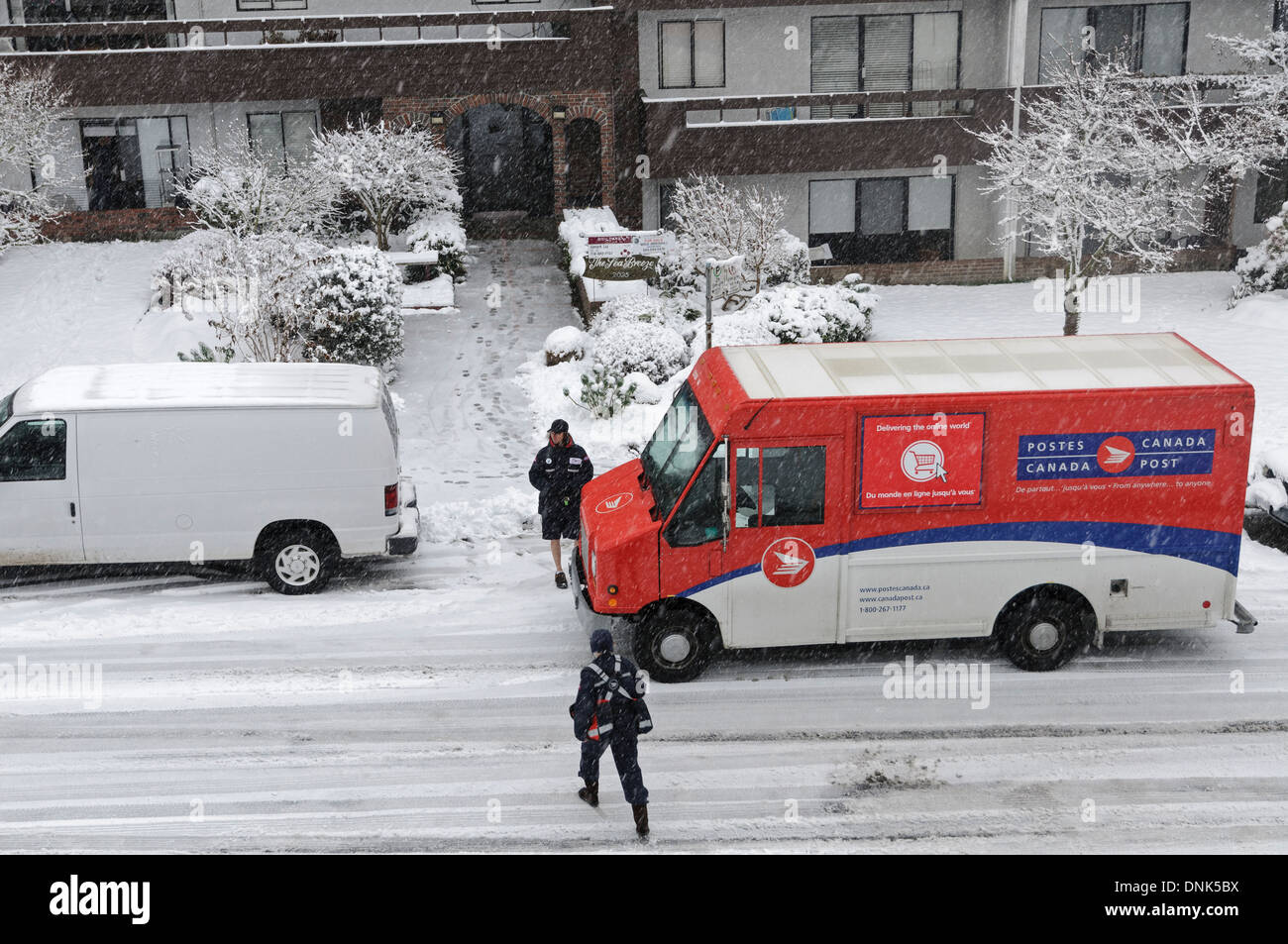 La livraison du courrier sur un jour neigeux Vancouver. Un transporteur lettre parle brièvement à un autre travailleur de Postes Canada dans un camion de livraison. Banque D'Images