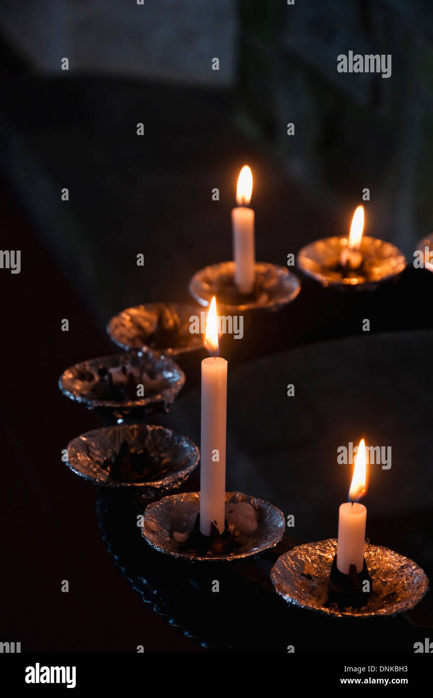 Des bougies allumées à l'intérieur d'une église de campagne Anglais, allumées en souvenir des êtres chers qui sont décédés. UK. Banque D'Images