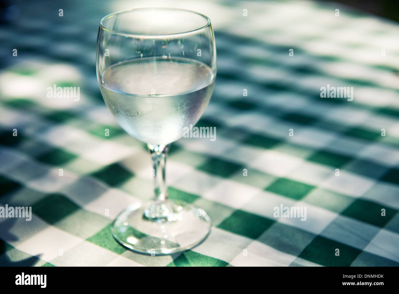 Verre d eau sur table avec nappe à carreaux vert Banque D'Images