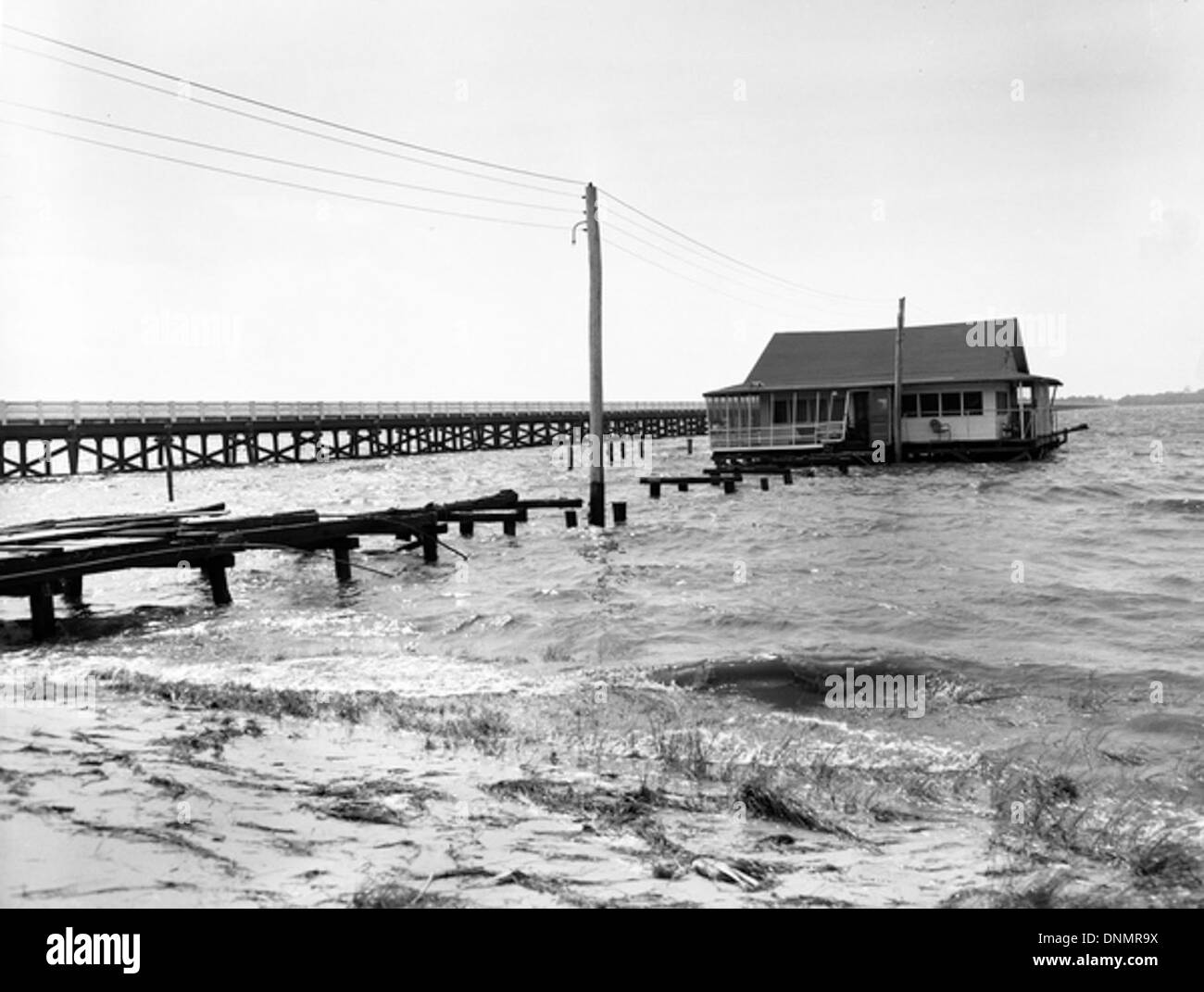 Un quai et une maison près d'Alligator point, en Floride, ont été endommagés lors de l'ouragan Florence dans les années 1950 L'image met en évidence l'impact de la tempête sur les infrastructures et les propriétés côtières. La région, située dans la baie d'Apalachee, dans le comté de Franklin, montre les effets des intempéries et de l'érosion sur les bâtiments et les quais. Banque D'Images