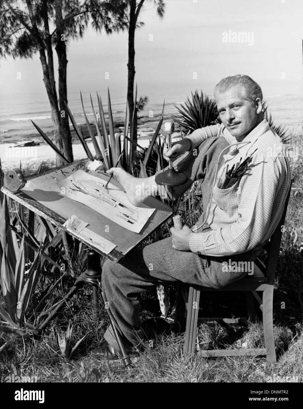 Le dessinateur Bandel Linn travaille à l'extérieur à Sarasota, en Floride, dans les années 1940, capturant l'essence de la région à travers son art tout en étant entouré de palmiers et de pins. Banque D'Images