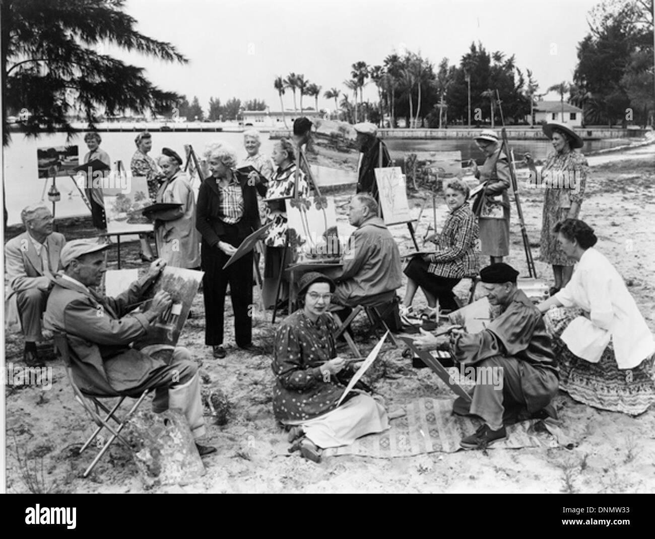 Un cours de peinture en plein air au Bayfront de Sarasota dans les années 1940, dans le cadre de la collection Joseph Janney Steinmetz. La scène montre des artistes peignant au milieu du paysage de Floride, avec des palmiers et de l'eau en arrière-plan. Banque D'Images