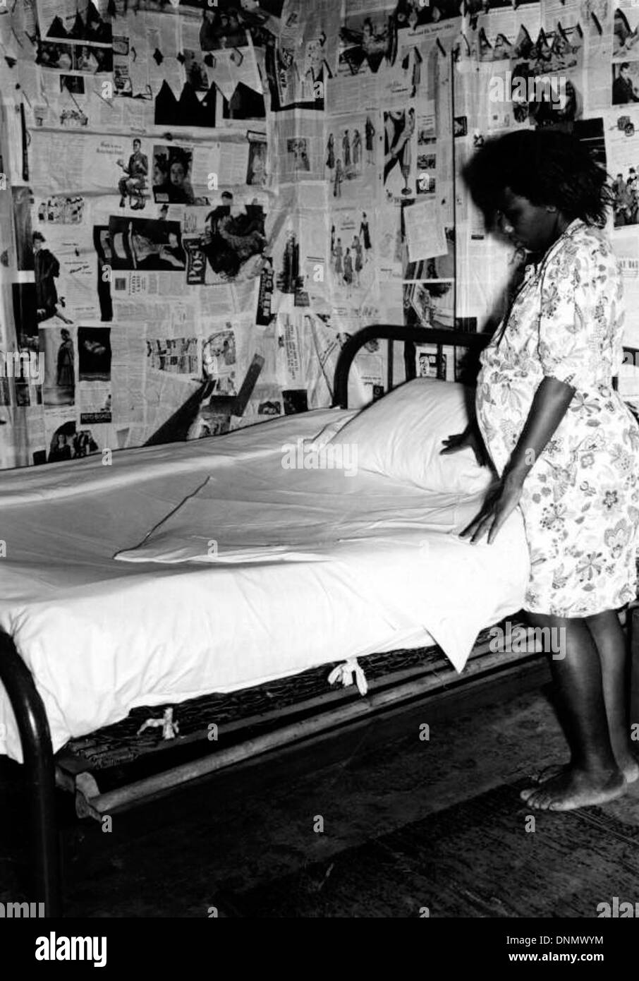 Une photographie des années 1940 d'une femme afro-américaine, la montrant pendant sa grossesse. L'image la capture à la maison, allongée sur un lit, sans chaussures, un reflet de la vie quotidienne des femmes enceintes pendant la période. Banque D'Images