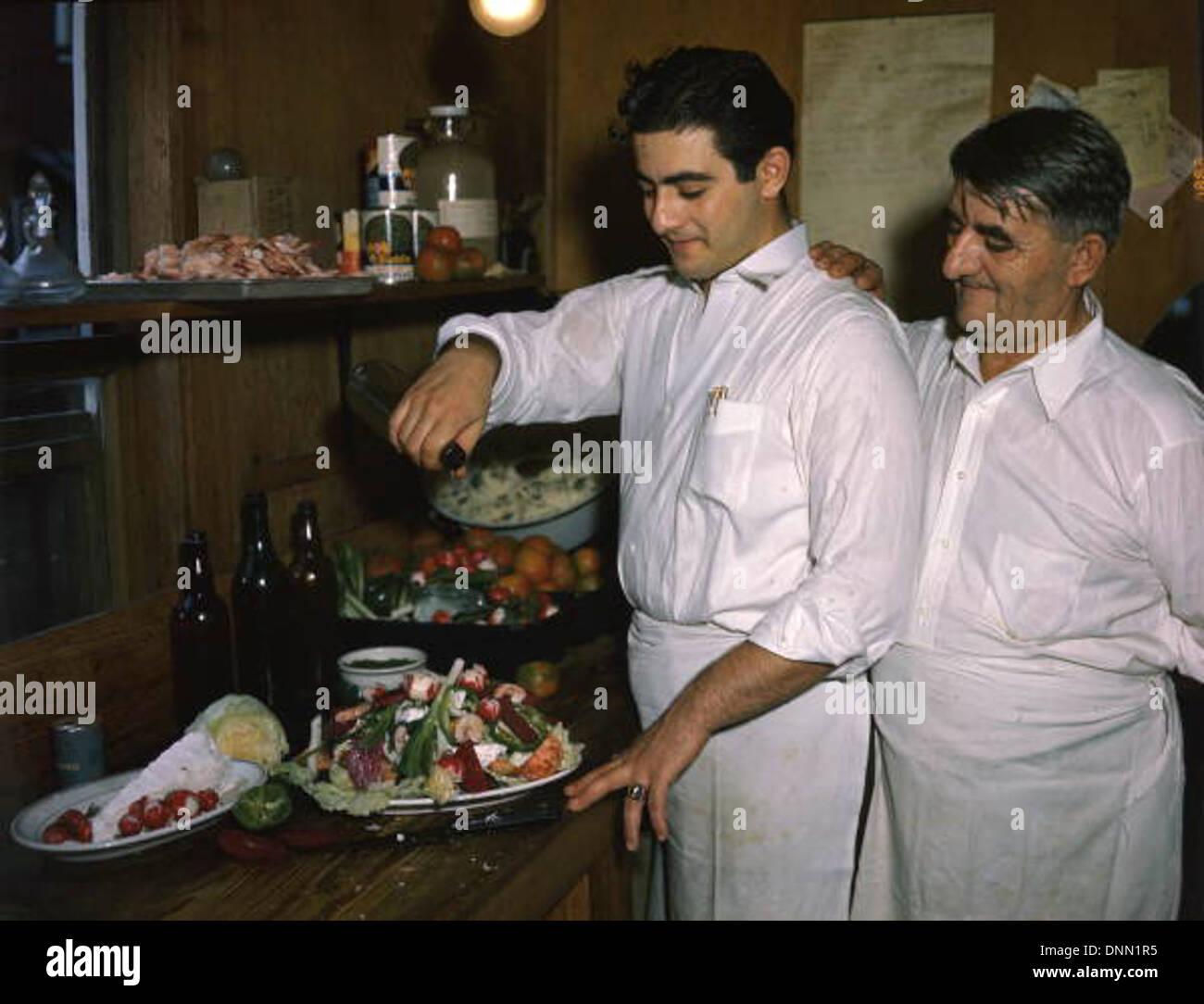 Louis et Michael Pappas préparent une salade grecque au Riverside Cafe à Tarpon Springs, Floride, dans les années 1940 Capturée par Joseph Janney Steinmetz, la photo reflète la culture gréco-américaine locale et l'importance du restaurant dans le comté de Pinellas. Banque D'Images