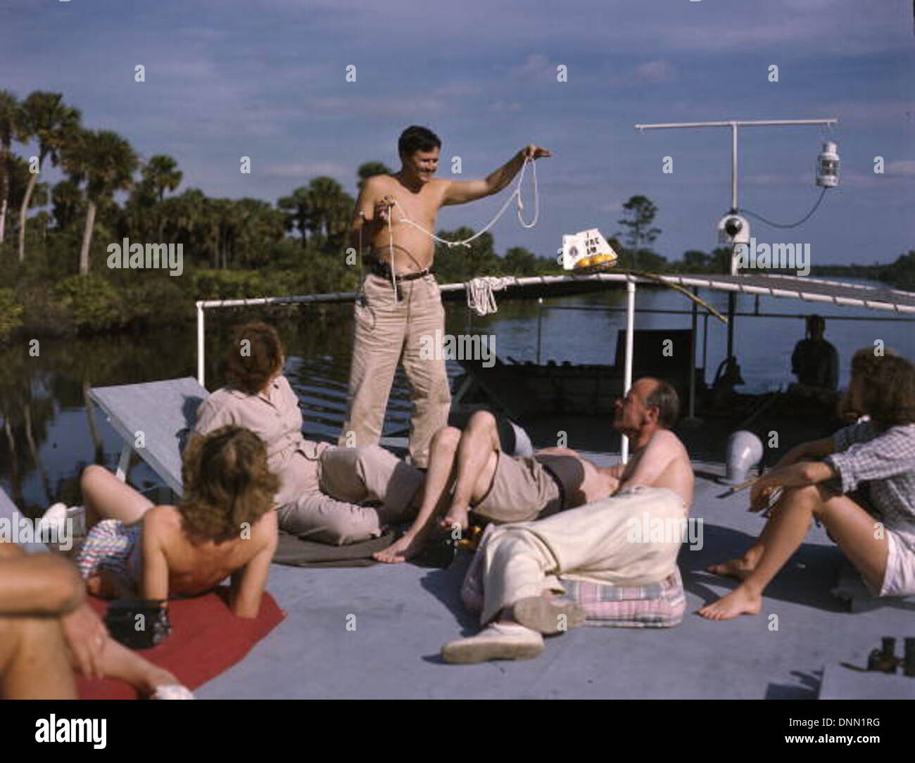 Joe Steinmetz est capturé en train d'effectuer un tour de magie à bord du shantyboat Lazy Bones sur la rivière Caloosahatchee à Fort Myers, en Floride, dans les années 1940 L'image met en évidence le mélange unique de divertissement et de voyage fluvial dans la région à cette époque. Banque D'Images