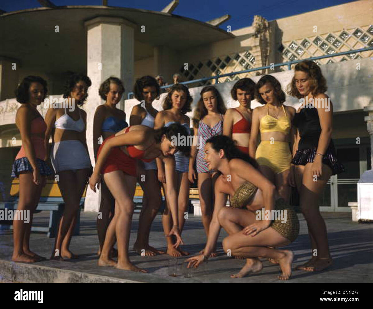 Sarasota Sun-Debs débutantes étant coaché sur la façon de ramasser des objets sur Lido Beach, Floride. L'événement, capturé par Joseph Janney Steinmetz, montre des femmes en maillot de bain lors d'une séance de coaching sur l'étiquette. Banque D'Images