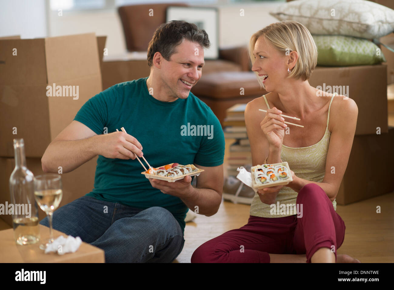 Couple eating sushi in new home Banque D'Images