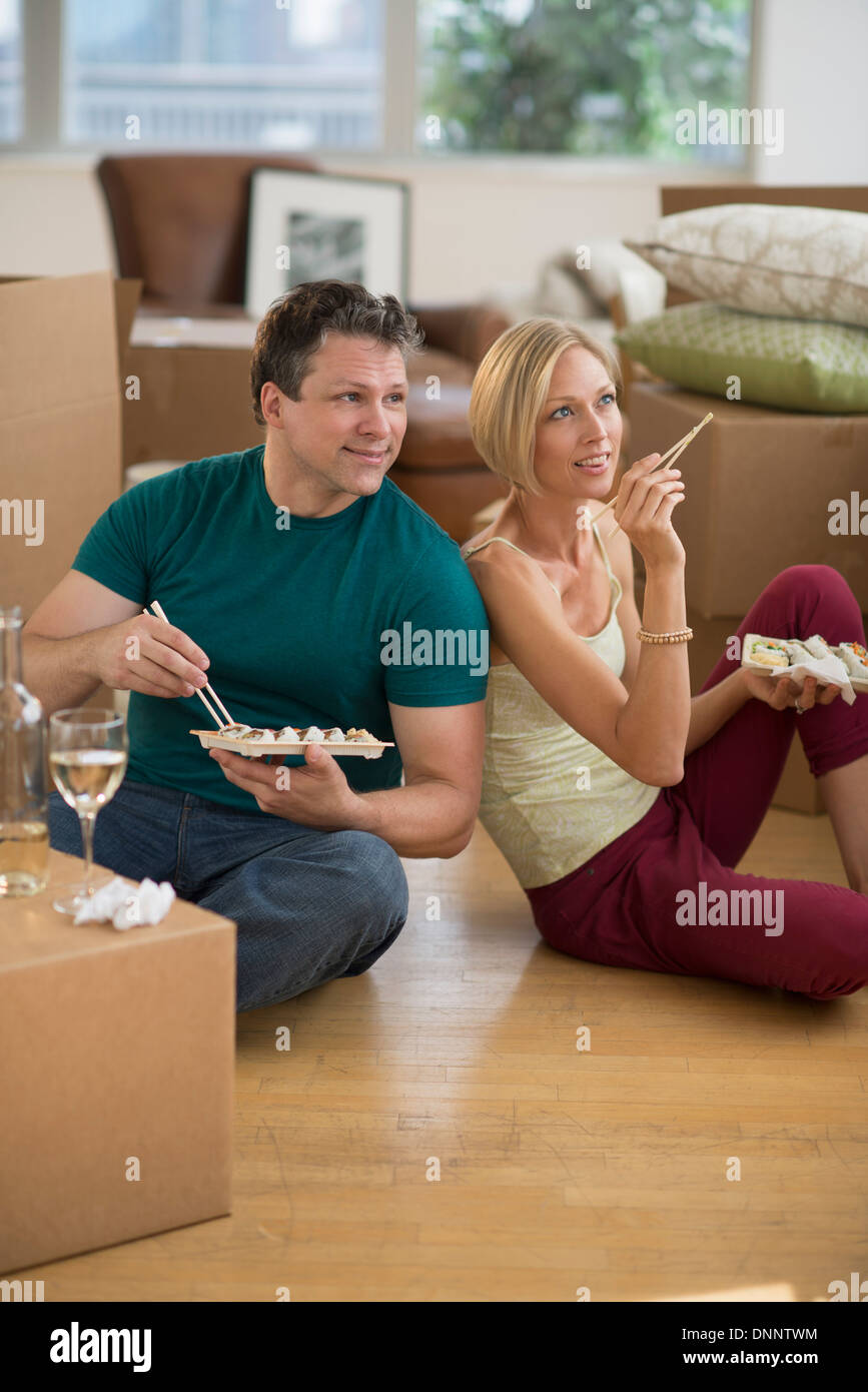 Couple eating sushi in new home Banque D'Images