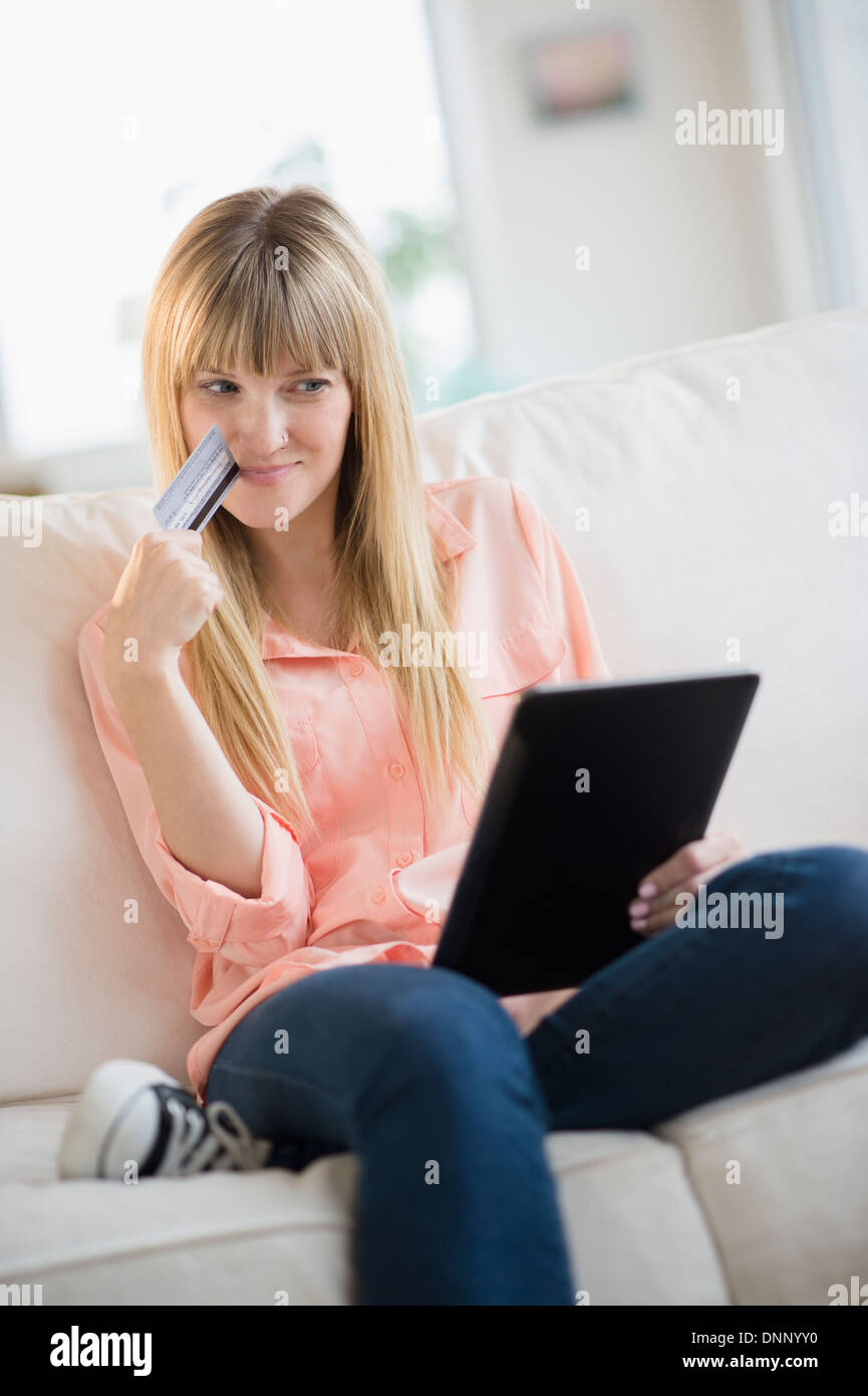 Woman sitting on sofa holding tablet pc Banque D'Images