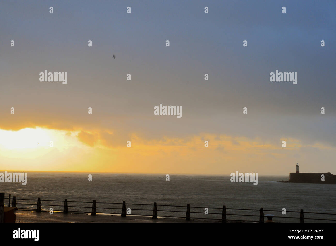 Newhaven, Sussex, UK. 3e janvier 2014. Dernière vue du soleil que les nuages et la pluie approche. Newhaven bras ouest phare sur la côte du Sussex de l'Est. Très haute marée et des vents forts prévus plus tard avec plus d'avertissements d'inondations émis plus à l'ouest le long de la côte à Shoreham. Crédit : David Burr/Alamy Live News Banque D'Images