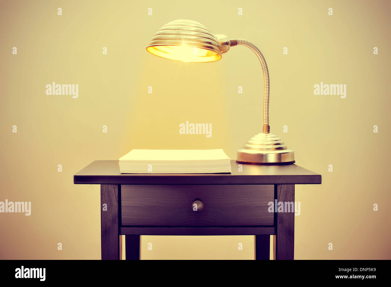 Photo d'une vieille lampe col de cygne et d'une pile de feuilles de papier vierge sur un bureau, avec un effet rétro Banque D'Images