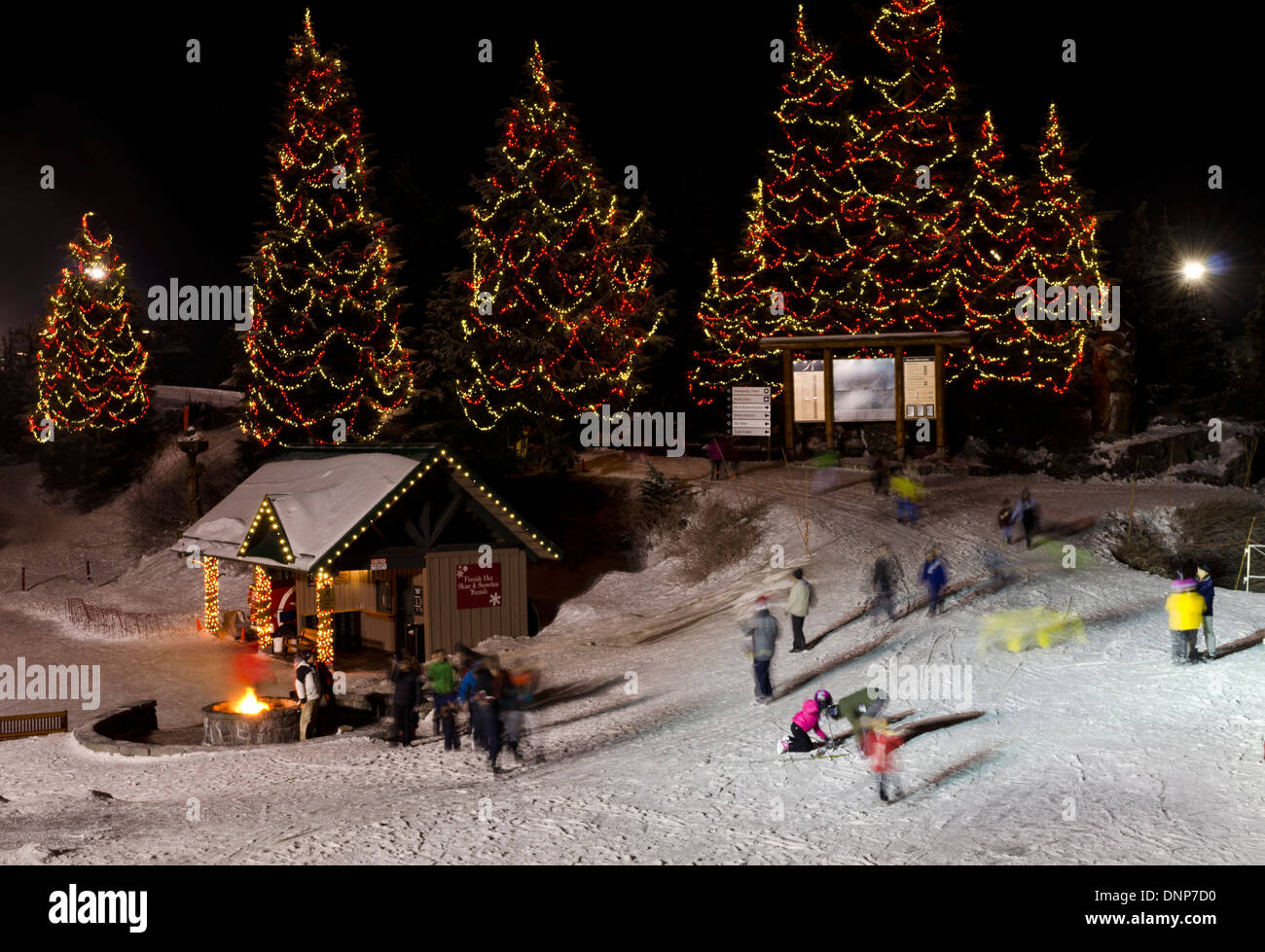 Les personnes bénéficiant de l'hiver au sommet de Grouse Mountain à Vancouver, Canada. Les arbres de Noël illuminés, patinoire, et un feu de joie. Banque D'Images