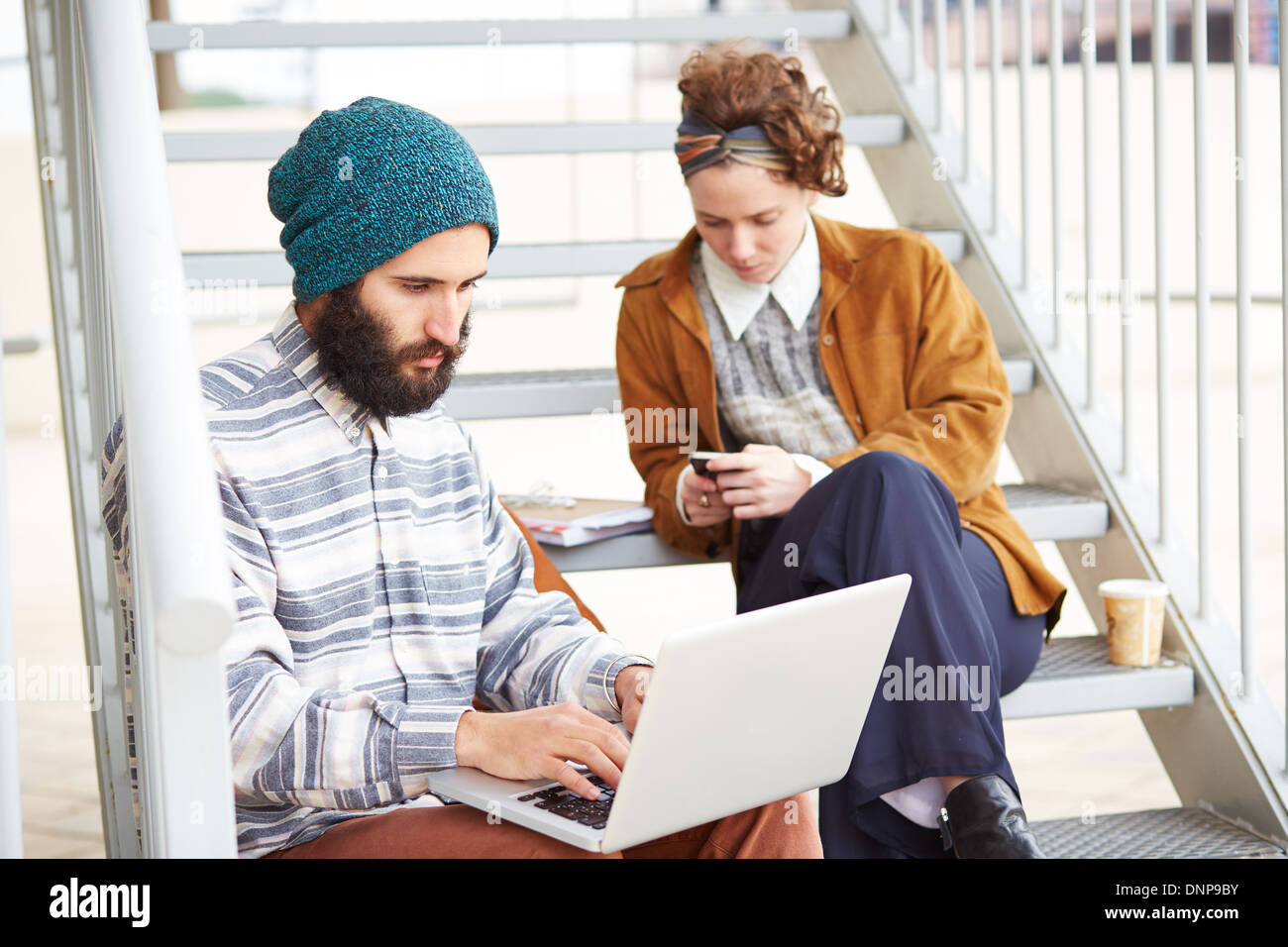 Couple Hipster en utilisant ordinateur et smartphone en campus universitaire Banque D'Images