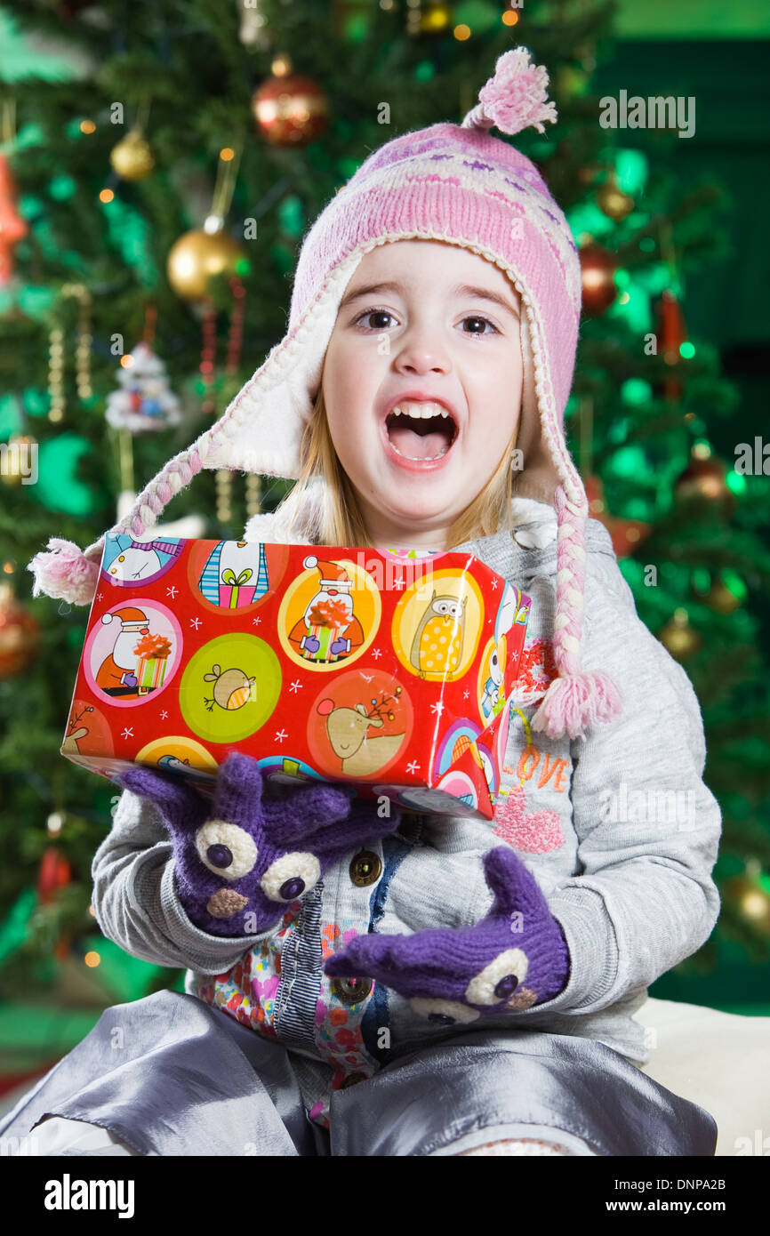 Une fillette de trois ans avec un arbre de Noël derrière elle Banque D'Images