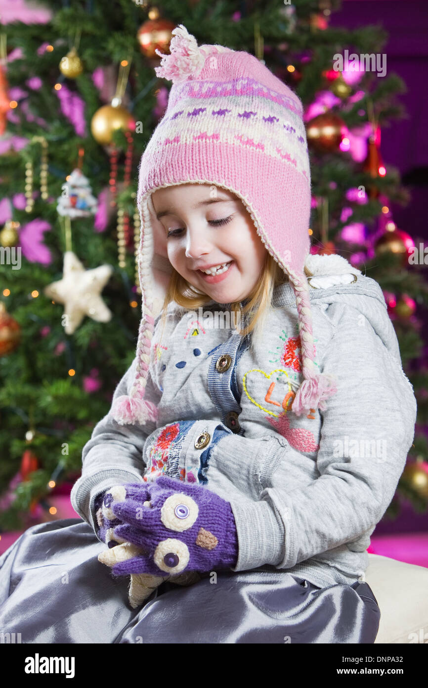 Une fillette de trois ans avec un arbre de Noël derrière elle Banque D'Images