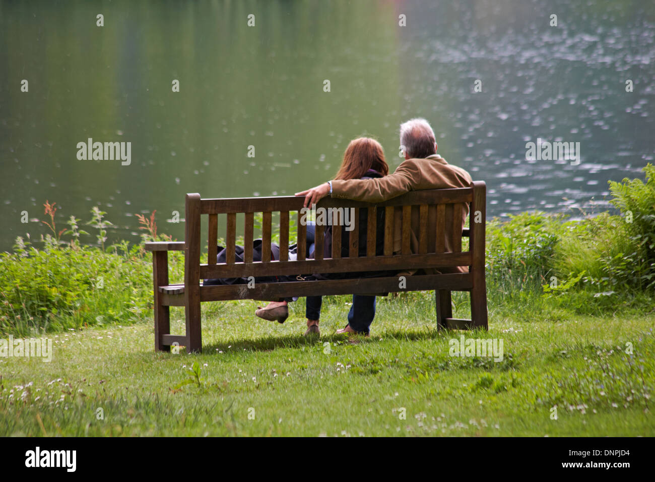Couple assis sur un banc à profiter de la vue sous la pluie Banque D'Images