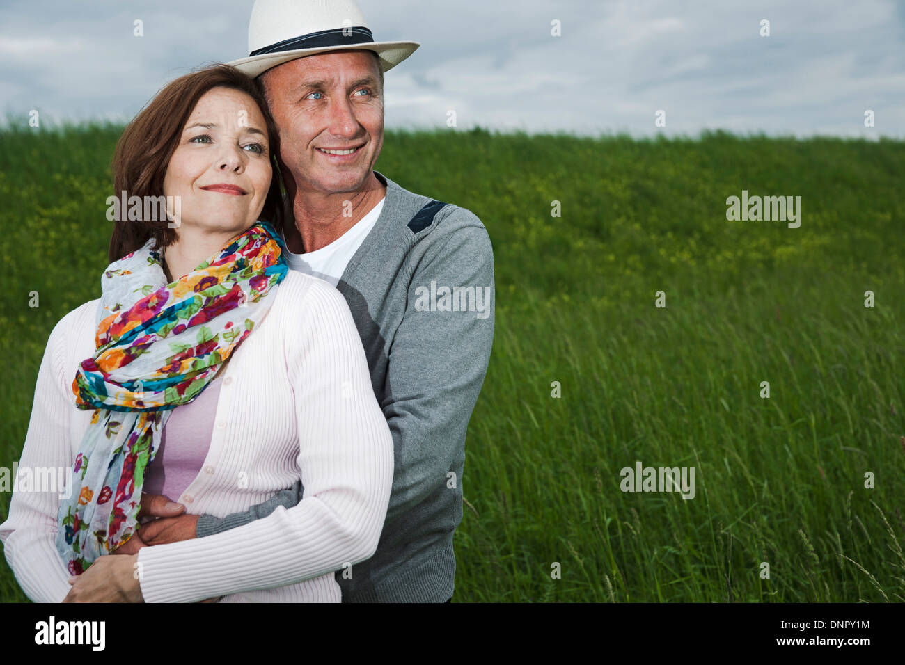 Close-up portrait of mature couple standing in field of grass, enlacés, Allemagne Banque D'Images