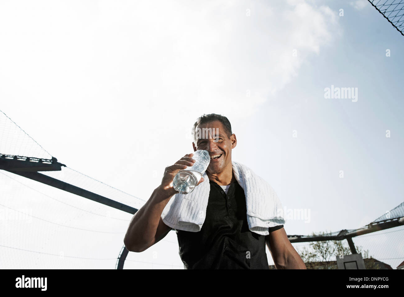Homme mature avec une serviette autour du cou, bouteille d'eau potable et à la caméra, à l'Allemagne Banque D'Images