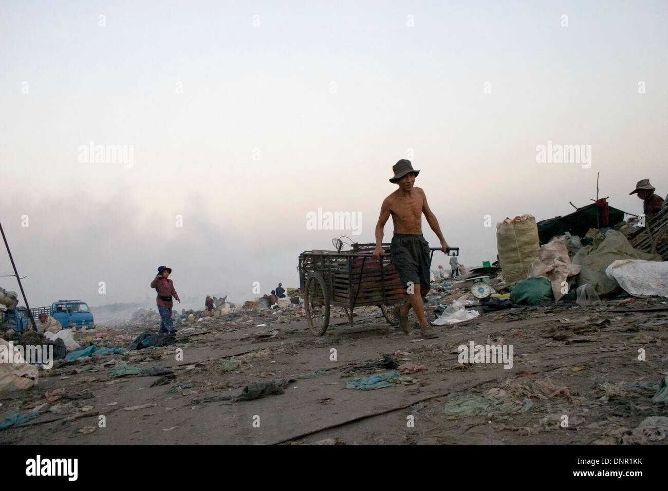 Un travailleur est tirant une charrette utilisée pour les matières toxiques à la décharge de Stung Meanchey à Phnom Penh, Cambodge. Banque D'Images