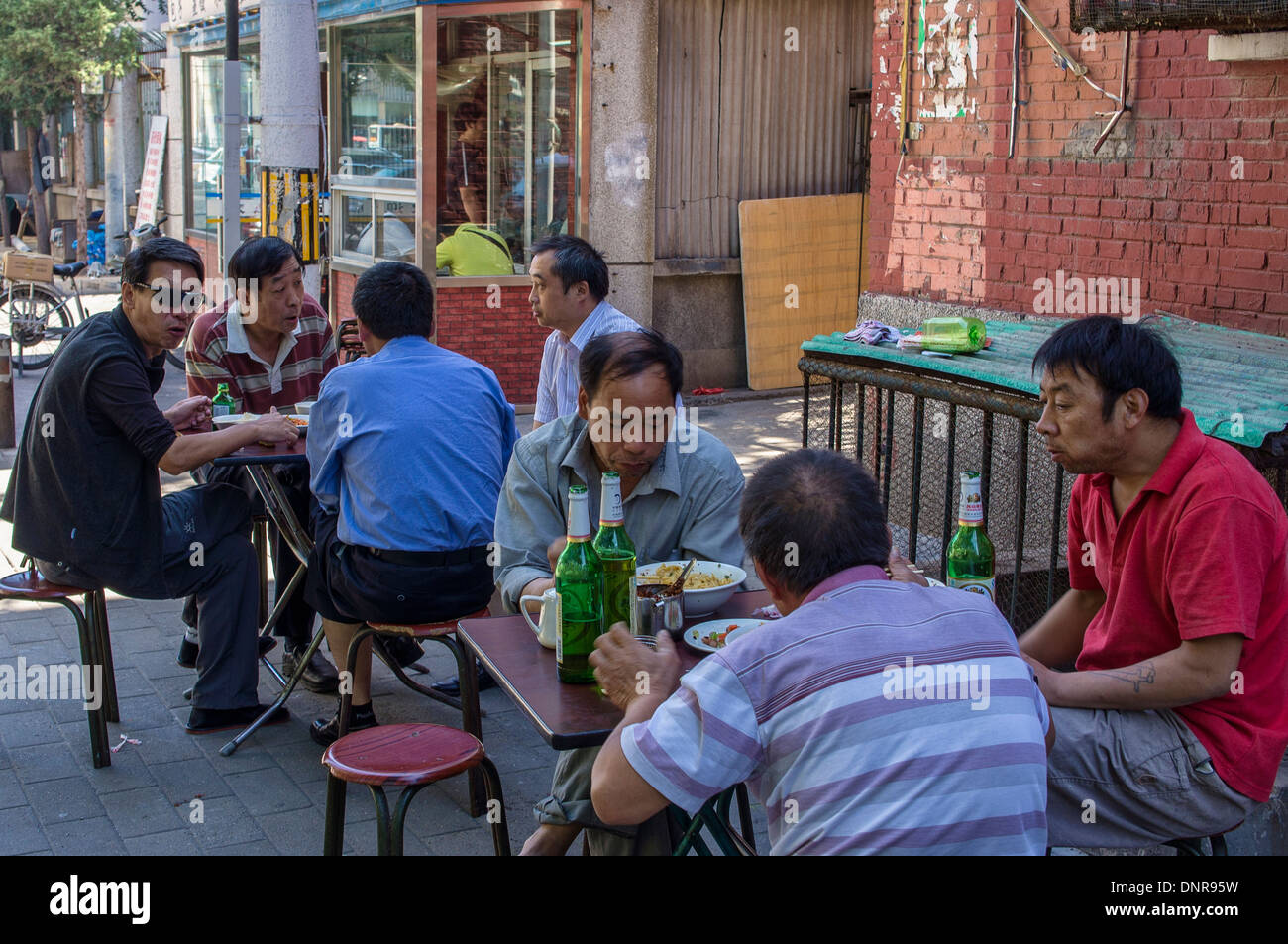 Les hommes de manger à l'Open-air table servi par Food Stand à Pékin, Chine Banque D'Images
