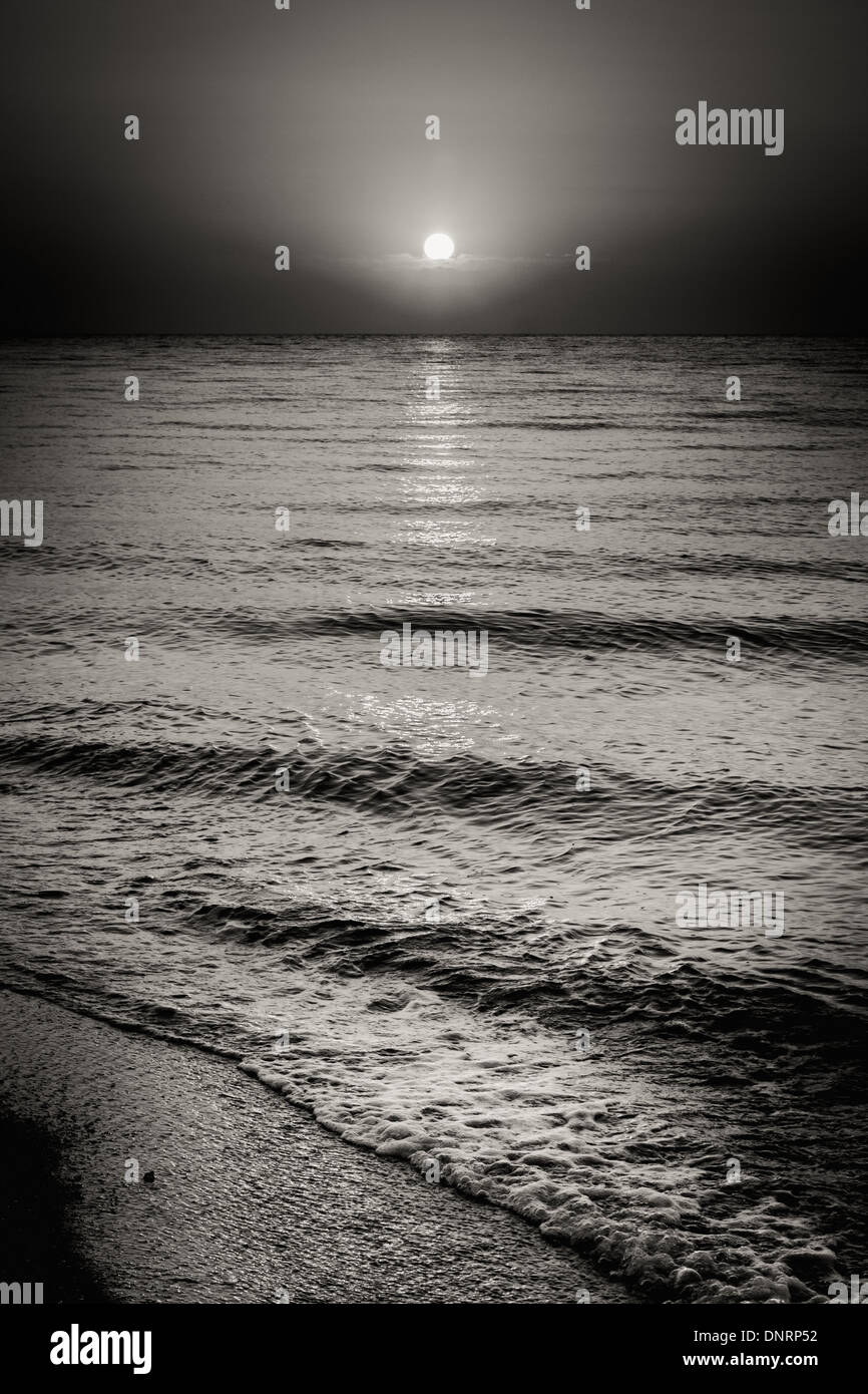 Le noir et blanc paysage spectaculaire avec de l'eau mer océan vagues et à fond Coucher de soleil Banque D'Images