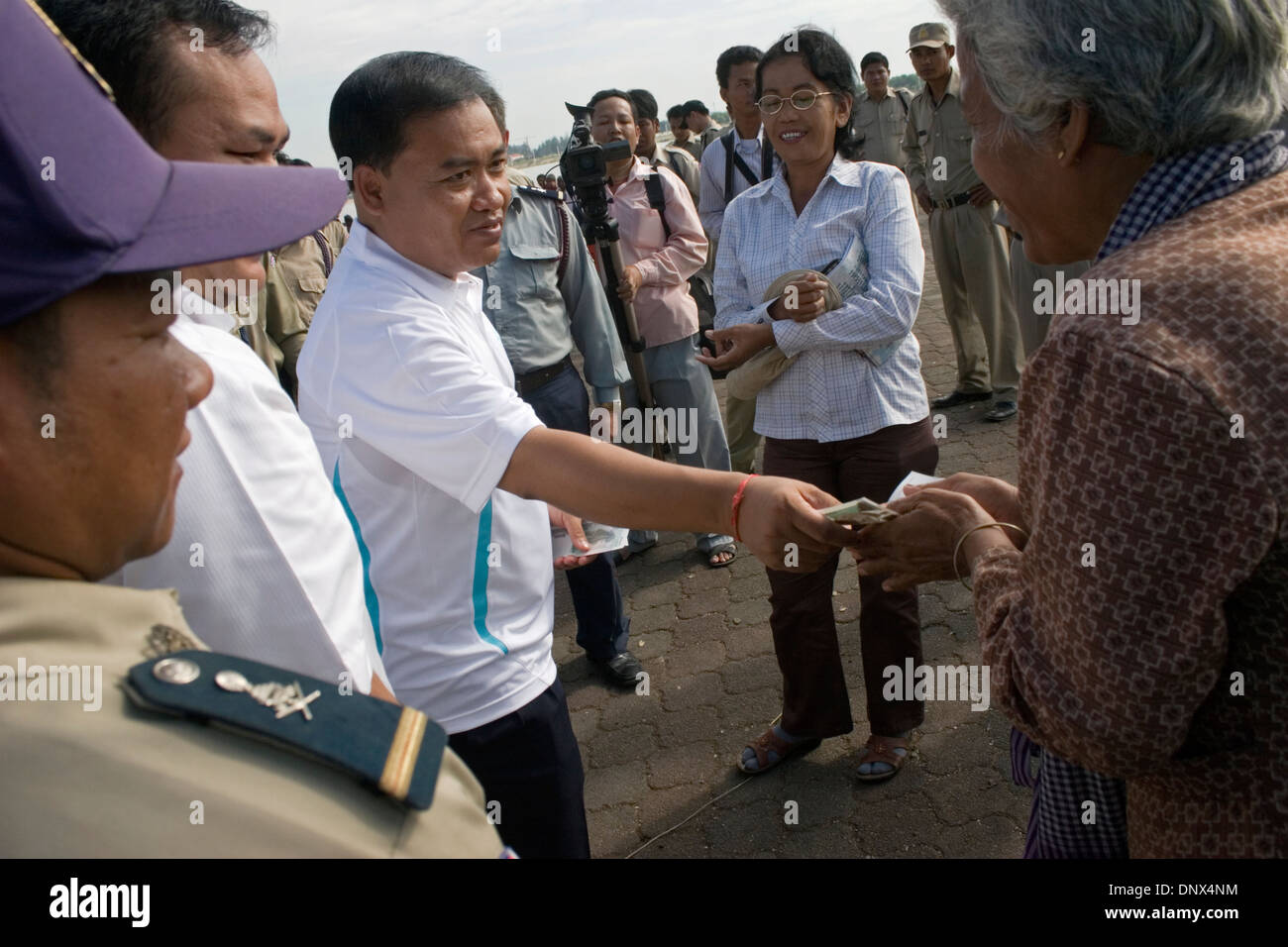 Un membre du parlement cambodgien est de donner une femme 5000 riel ($1.25) près du fleuve Mékong à Phnom Penh, Cambodge. Banque D'Images