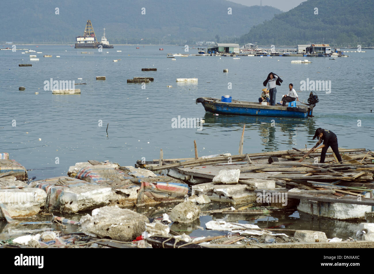 Les pêcheurs et les travailleurs se déchargent du bois parmi des briques, des boîtes et des emballages en plastique et en polystyrène brisés et jetés dans un port où les bateaux de pêche déchargent leurs prises. La pollution est si importante que certains navires sont coincés, incapables de se déplacer. Les exploitations de pêche chinoises utilisent également largement des boîtes en polystyrène, des dispositifs de flottaison et des emballages, ce qui entraîne des dommages environnementaux et pollue la mer et les océans, car ils brisent et abaissaient les intempéries ni ou en raison d'une mise au rebut imprudente. © Olli Geibel Banque D'Images