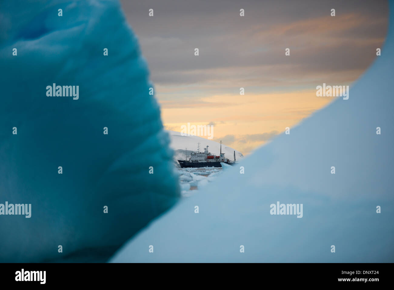 L'ANTARCTIQUE - un bateau de croisière dans l'Antarctique la distance perçue par les icebergs, que le soleil couchant jette une lumière dorée sur l'horizon. Banque D'Images