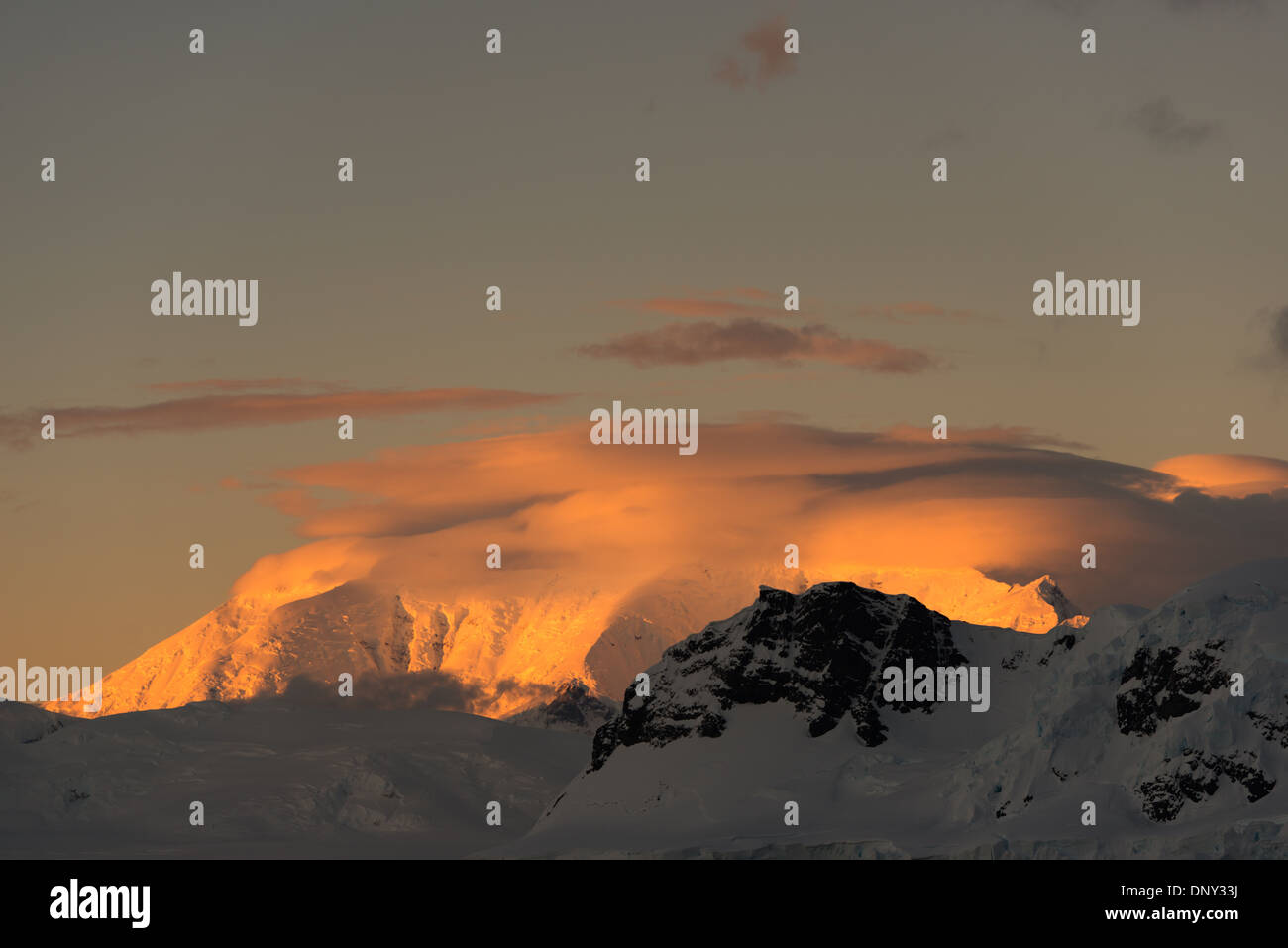 L'ANTARCTIQUE - le soleil couchant jette une lueur orange magnifique sur les nuages et les montagnes de l'Antarctique spectaculaire paysage de Paradise Harbour, l'Antarctique. Banque D'Images