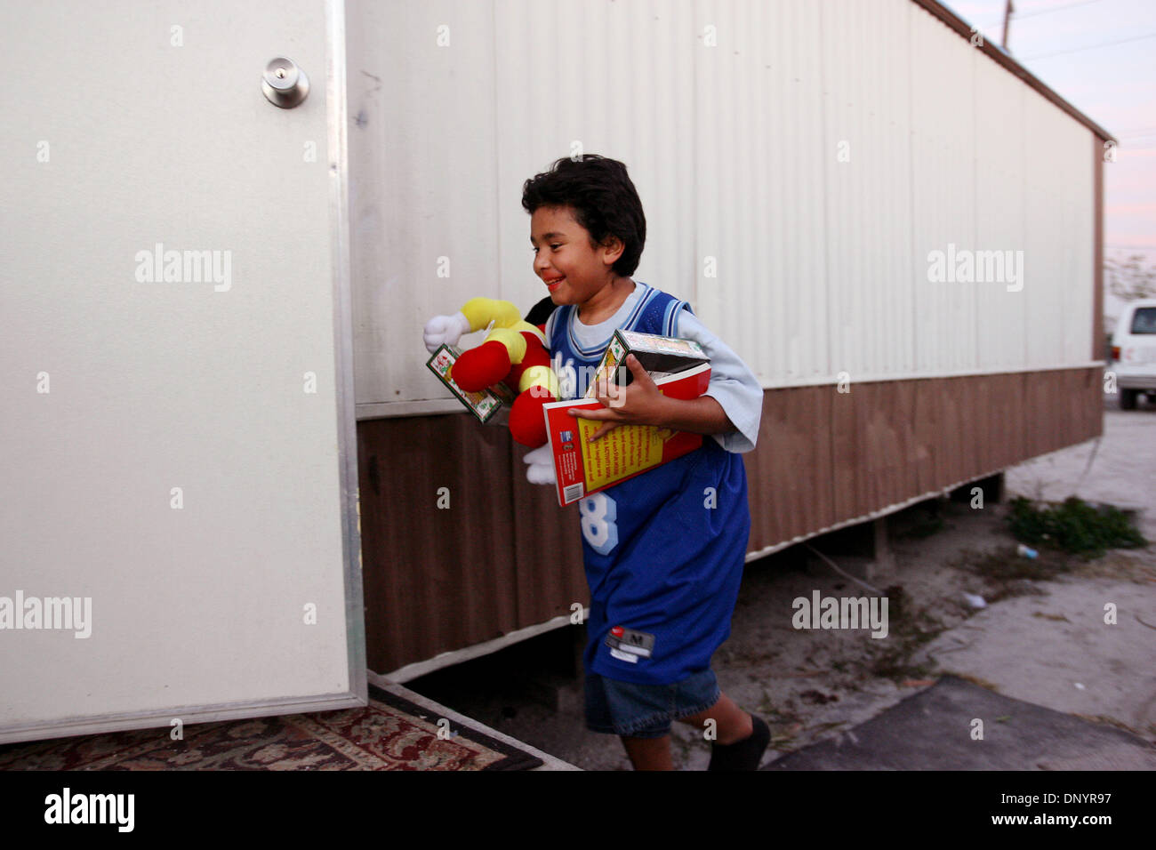 Feb 07, 2006 ; Pahokee, FL, USA ; Ruiz Junior, 11, entre dans sa maison avec des cadeaux remis aux familles par les églises à une fête de Noël organisée par Larry Wright, de Pahokee, pour les familles d'Usher's Trailer Park à Pahokee mardi. Les résidents du parc étaient sans électricité pendant 101 jours après l'ouragan Wilma a frappé la région. Trois églises de l'espace a permis de présenter, de l'alimentation et le caillot Banque D'Images