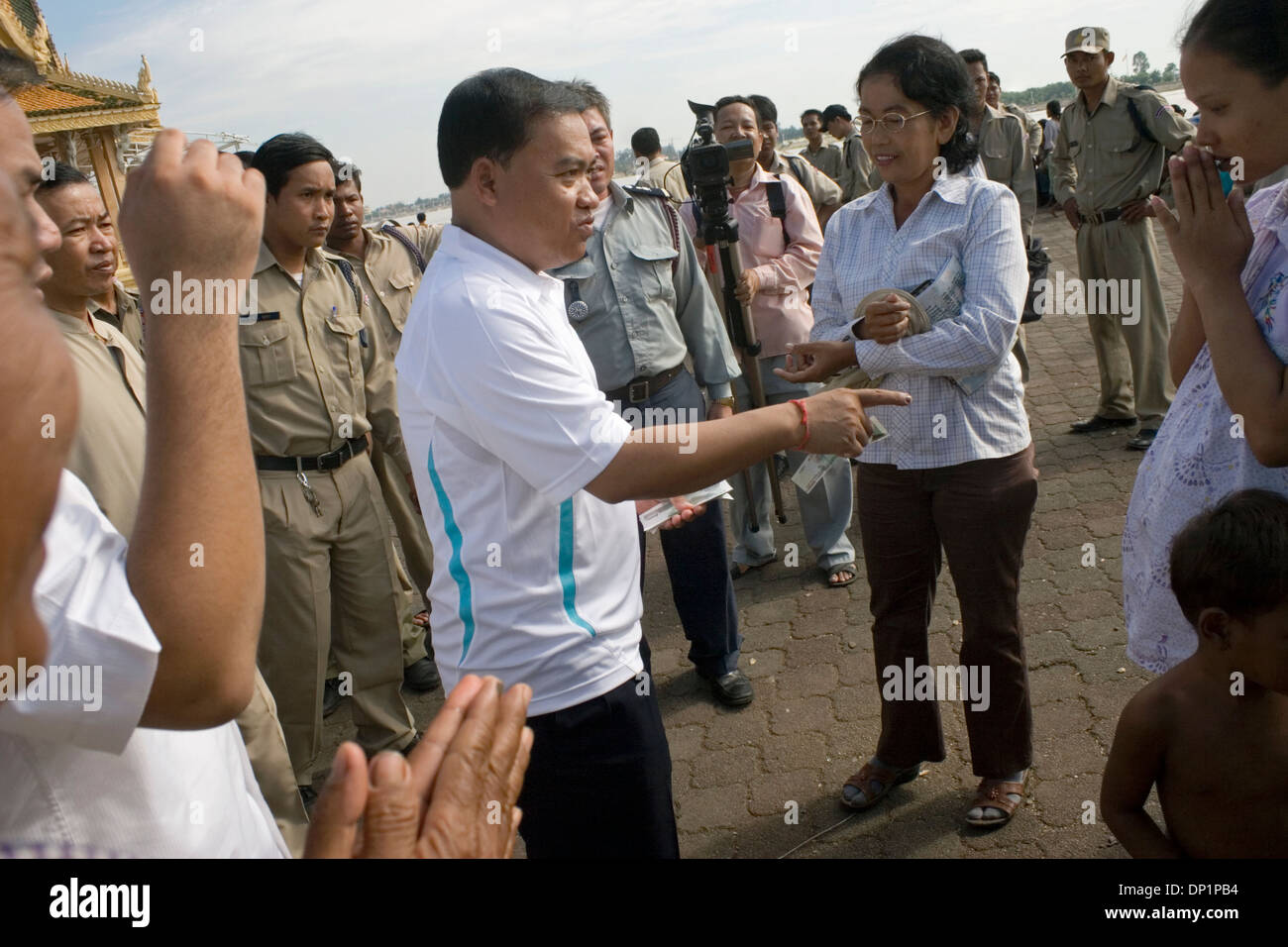 Un membre du parlement cambodgien s'apprête à donner une femme 5000 riel ($1.25) près du fleuve Mékong à Phnom Penh, Cambodge. Banque D'Images