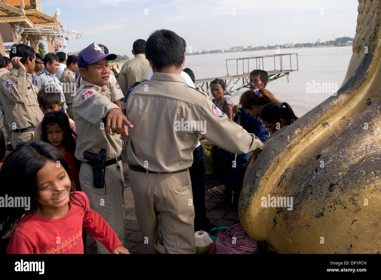 La police est de contrôler une foule d'enfants cambodgiens pauvres près du fleuve Mékong à Phnom Penh, Cambodge. Banque D'Images