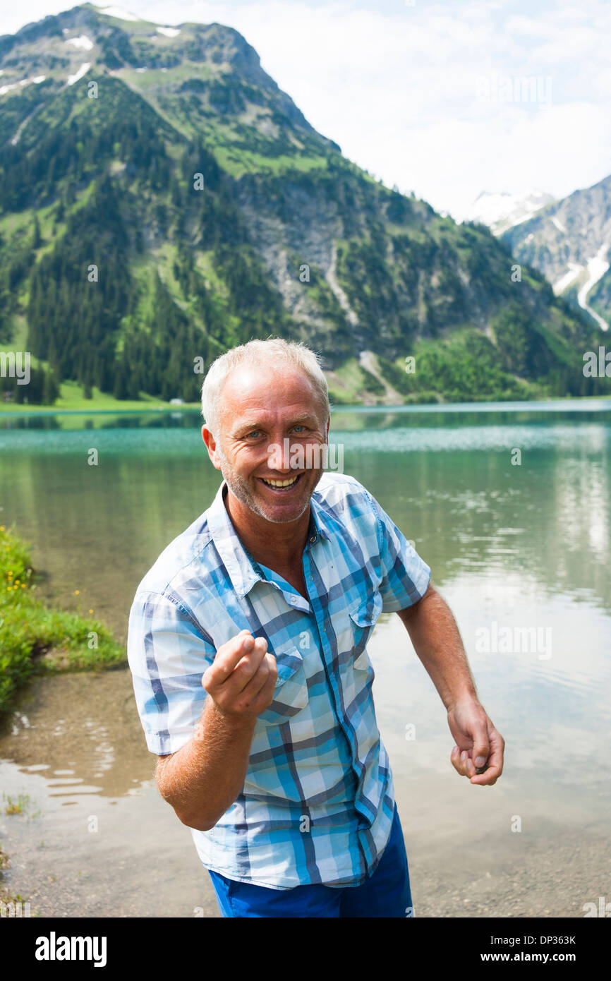 Portrait of mature man Skipping Stones au lac Woman Jogging in forest, Autriche Banque D'Images
