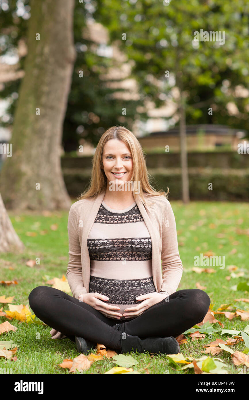 Pregnant woman sitting in park Banque D'Images