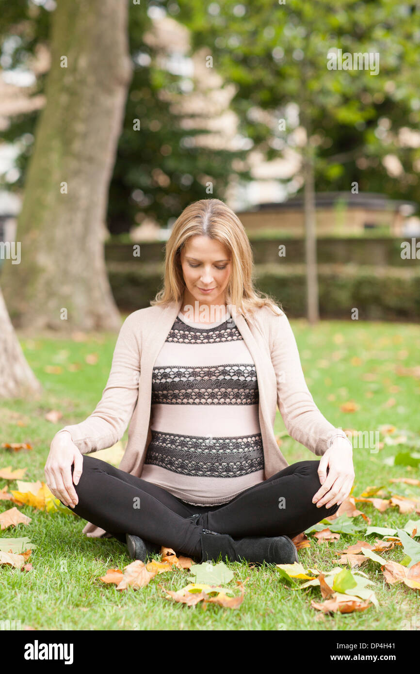 Pregnant woman sitting in park Banque D'Images